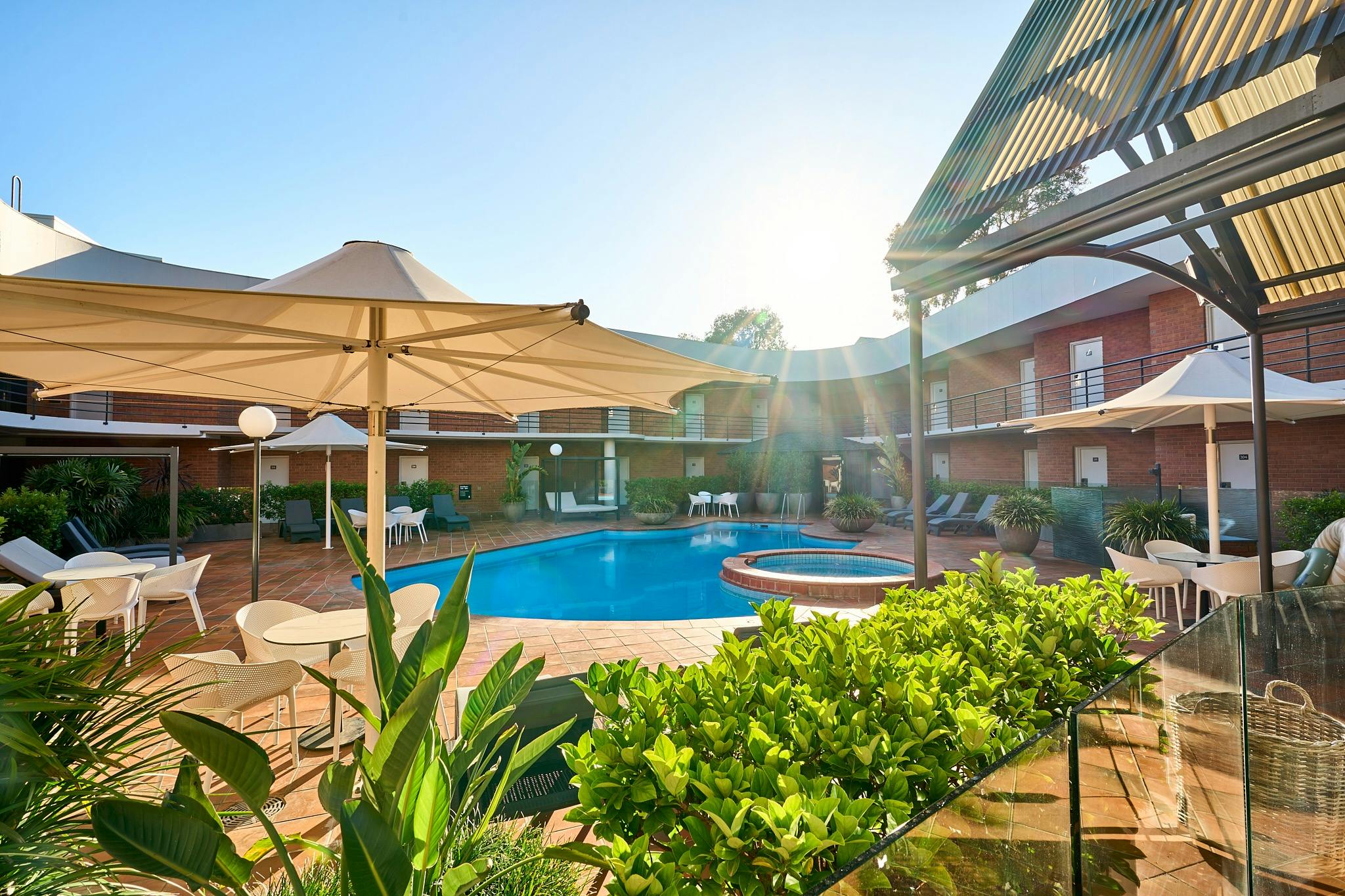 Landscaped outdoor area with lounges, tables, chairs overlooking heated pool, spa and sauna
