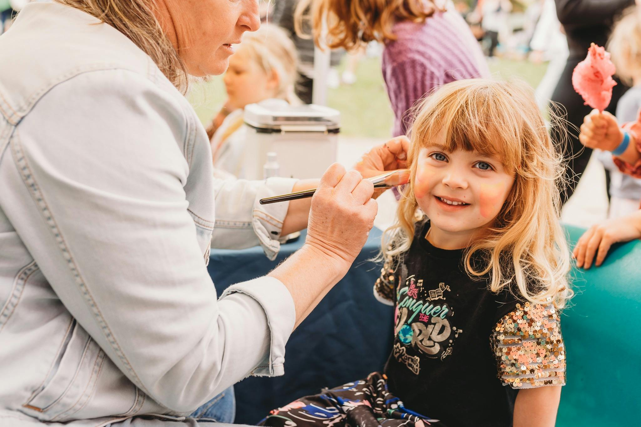 A smiling girl looking at camera having her face painted