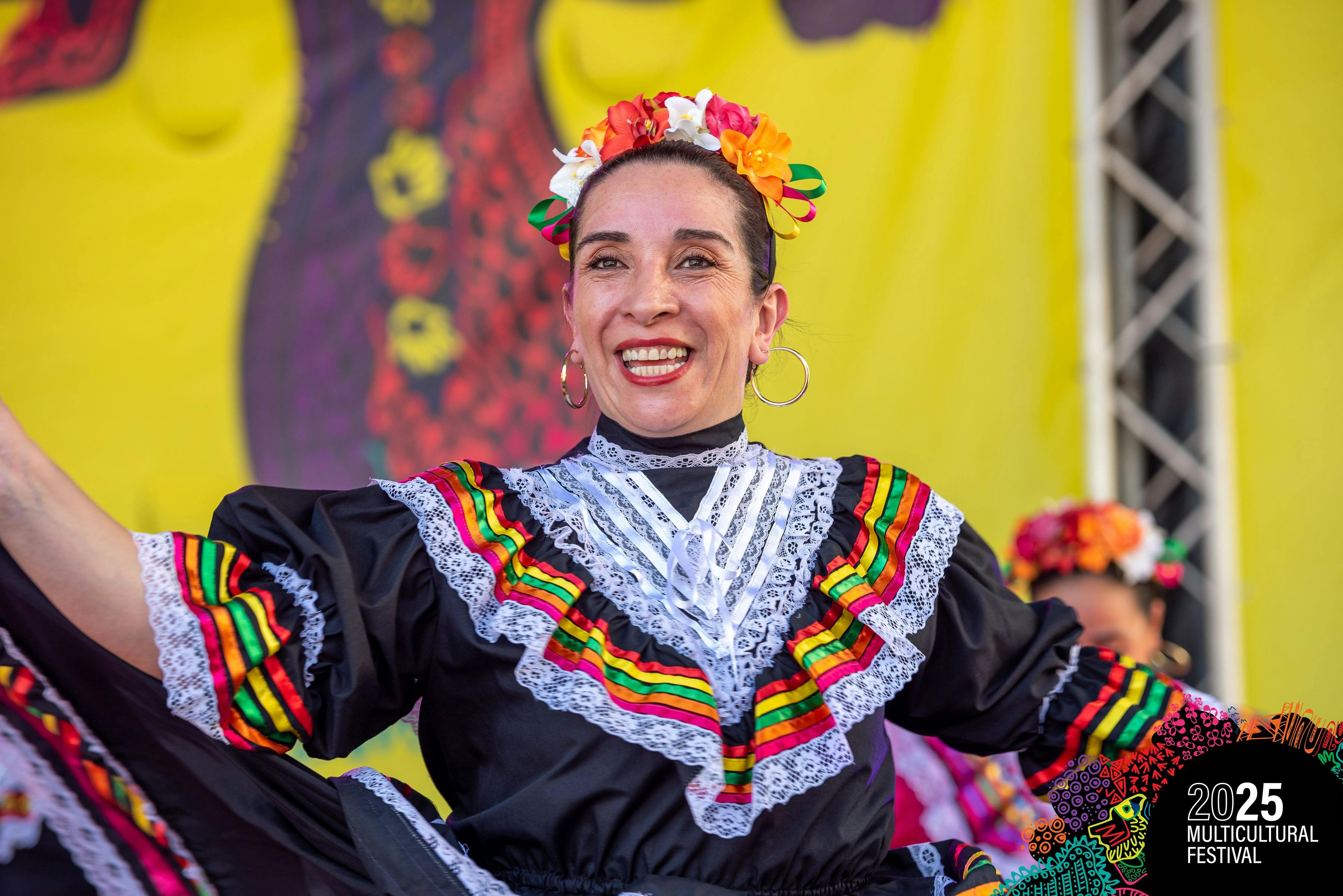 Woman in traditional dancing costume performing on stage with flower ehadband.