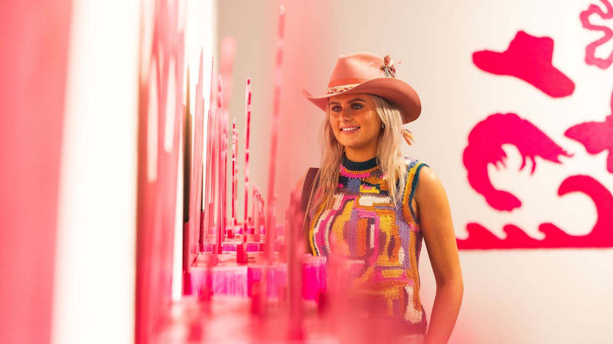 Young woman looking at a bright pink art installation