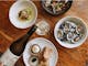 An image of food dishes spread out on the table at Elm Dining while wine is being poured