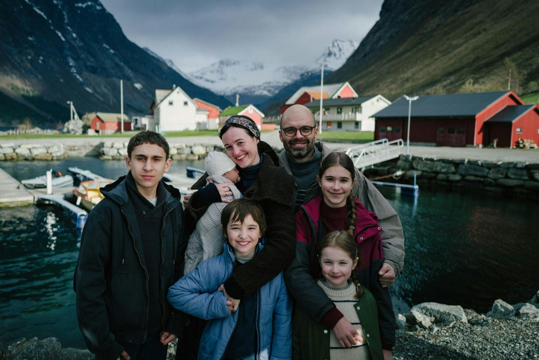 A family poses smiling in front of a Norwegian Fjord