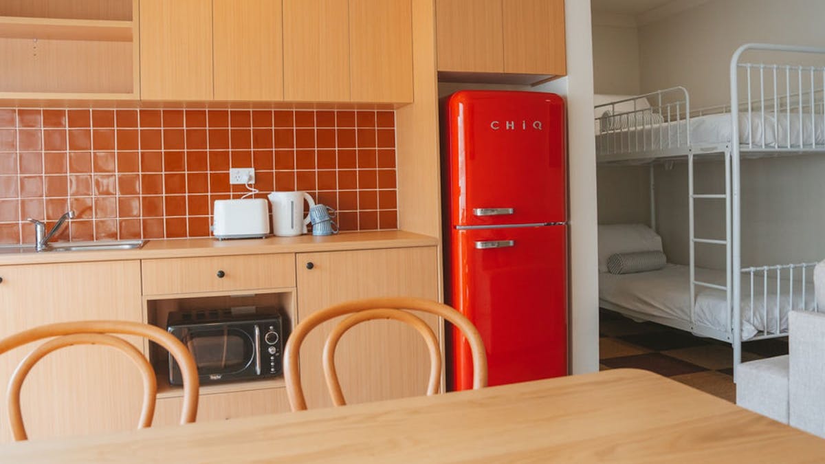 Family room kitchenette with retro red fridge, dining table and bunk beds at Hotel Allen.