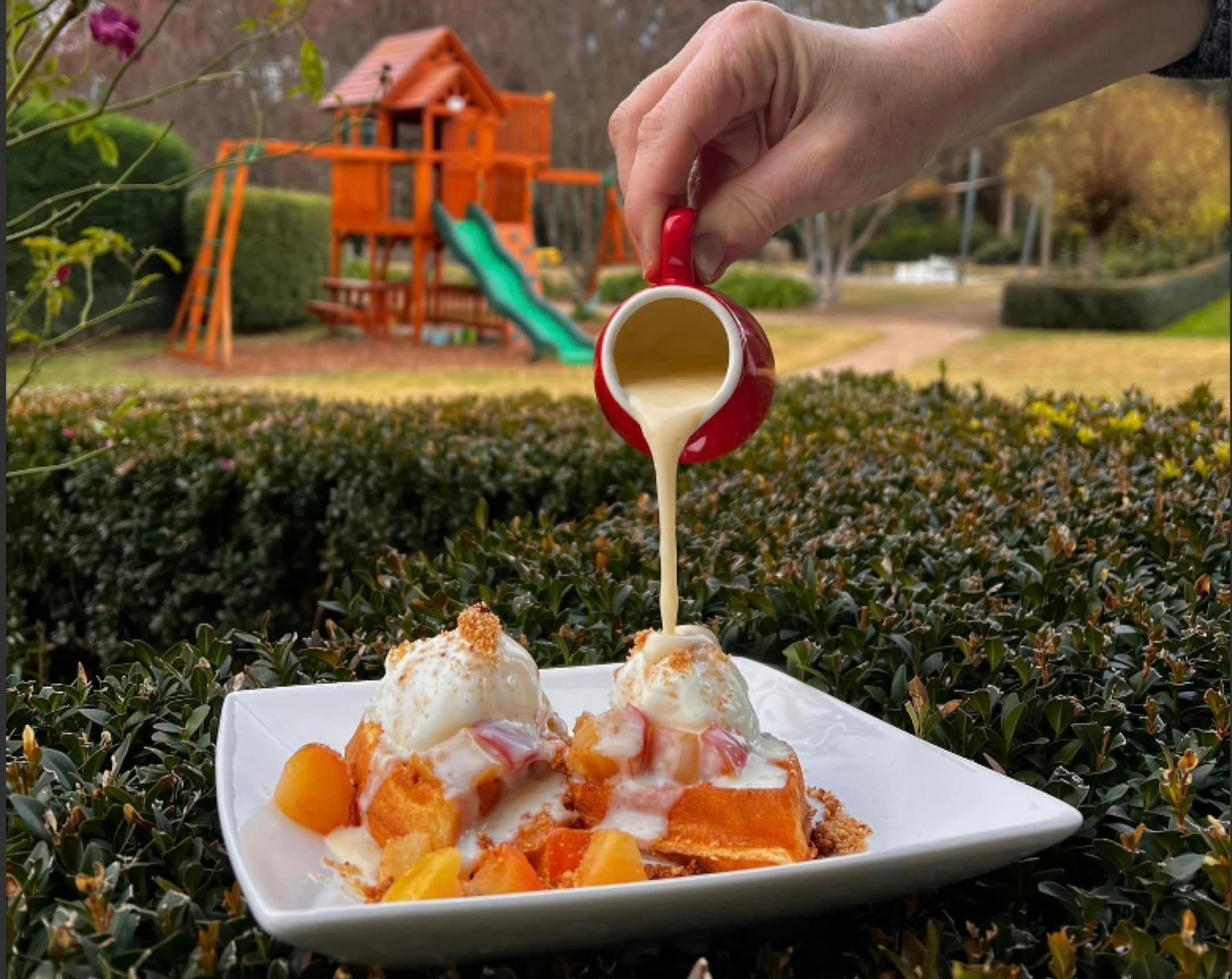 Tania pouring custard over the very yummy apple pie waffle at Brookfield Maze