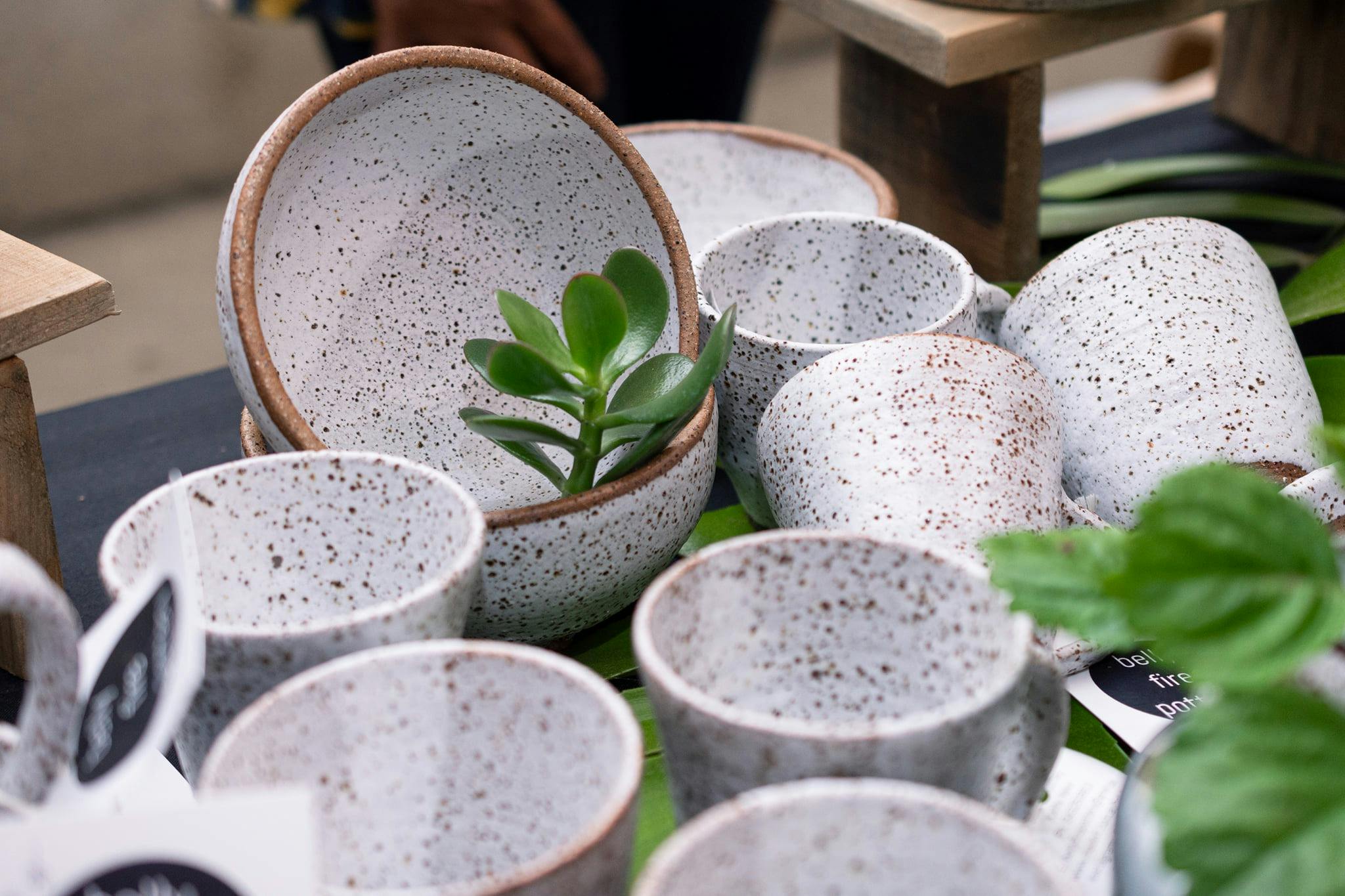 A close up shot of handmade speckled stoneware cups, mugs and bowls