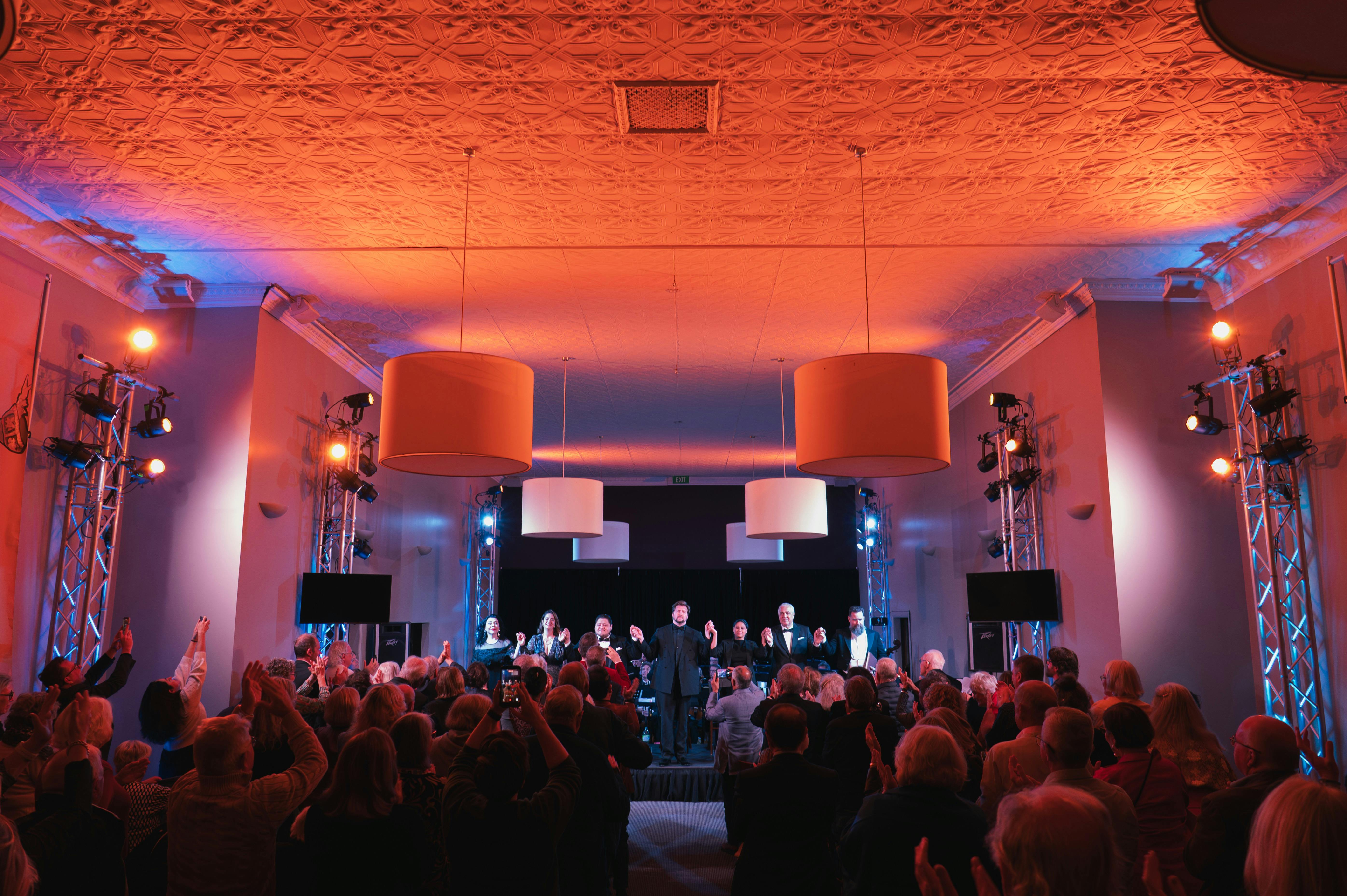 A music hall filled with people in red/orange light