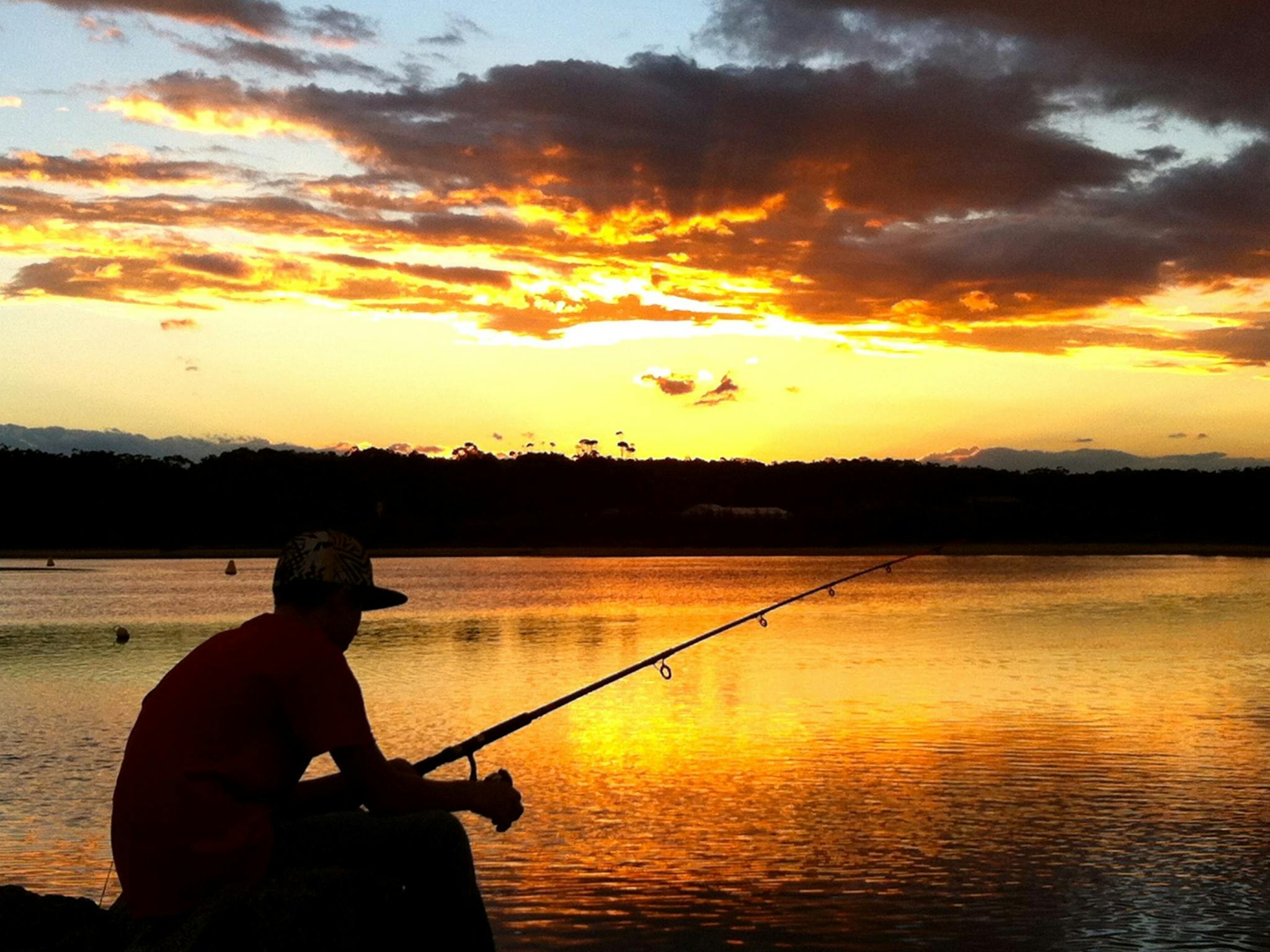 A man fishing at the Deua River at sunset