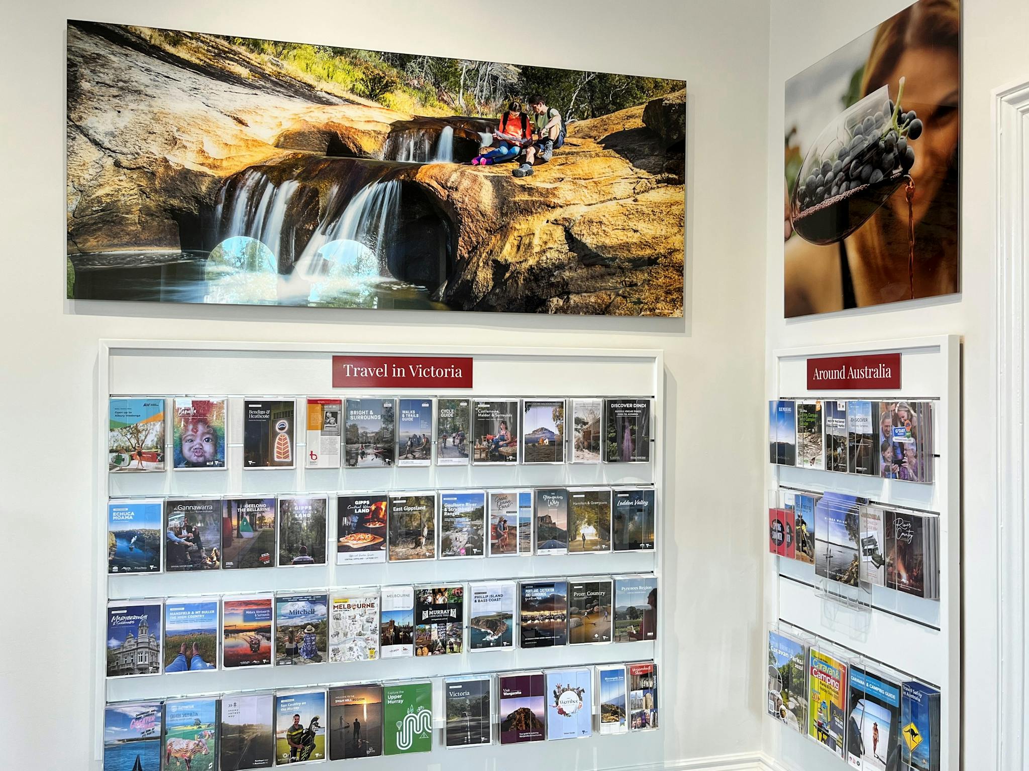 Large image of a rocky waterfall above a wall of travel booklets