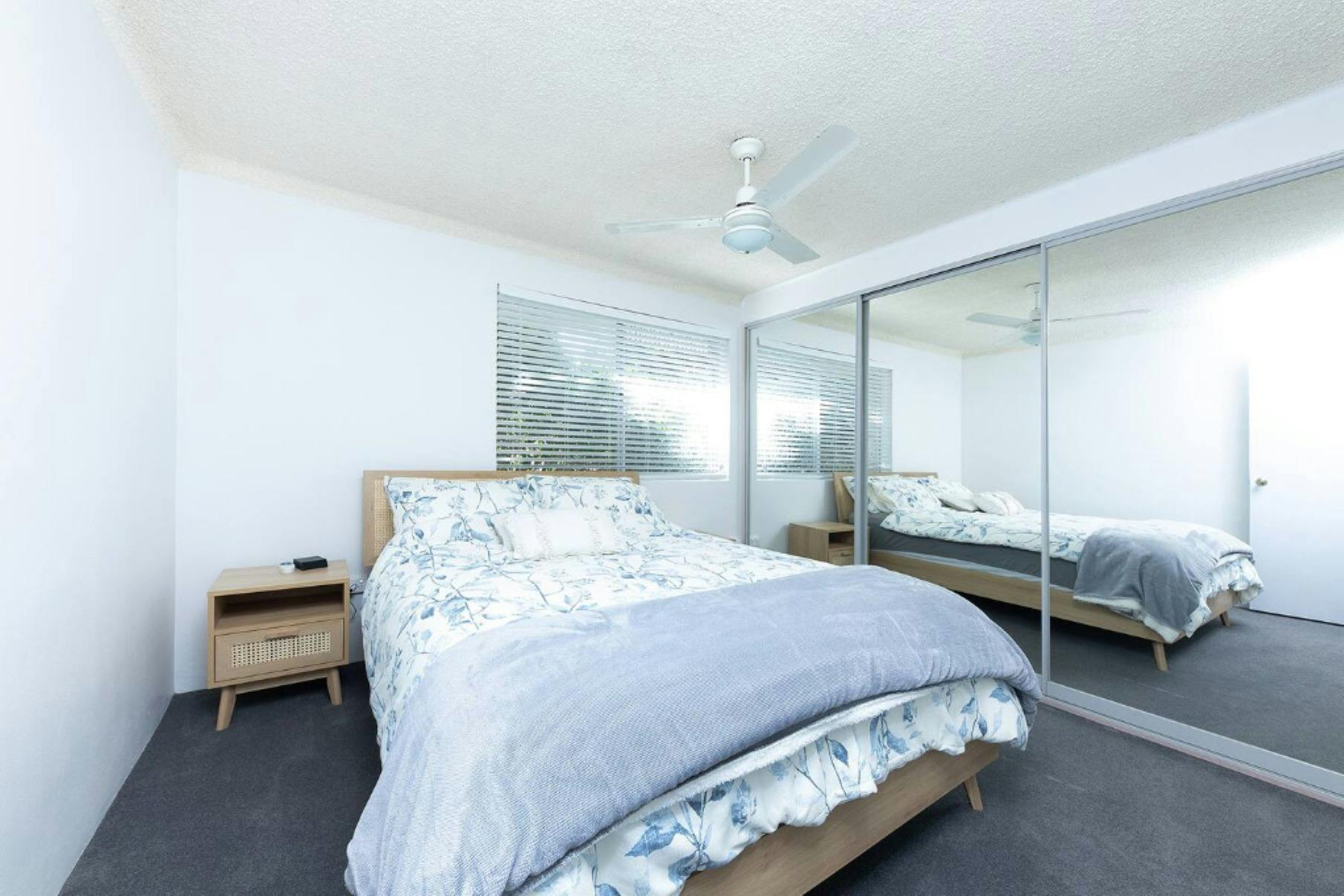 クイーンベッド、シーリングファン、鏡張りのワードローブを備えたベッドルーム