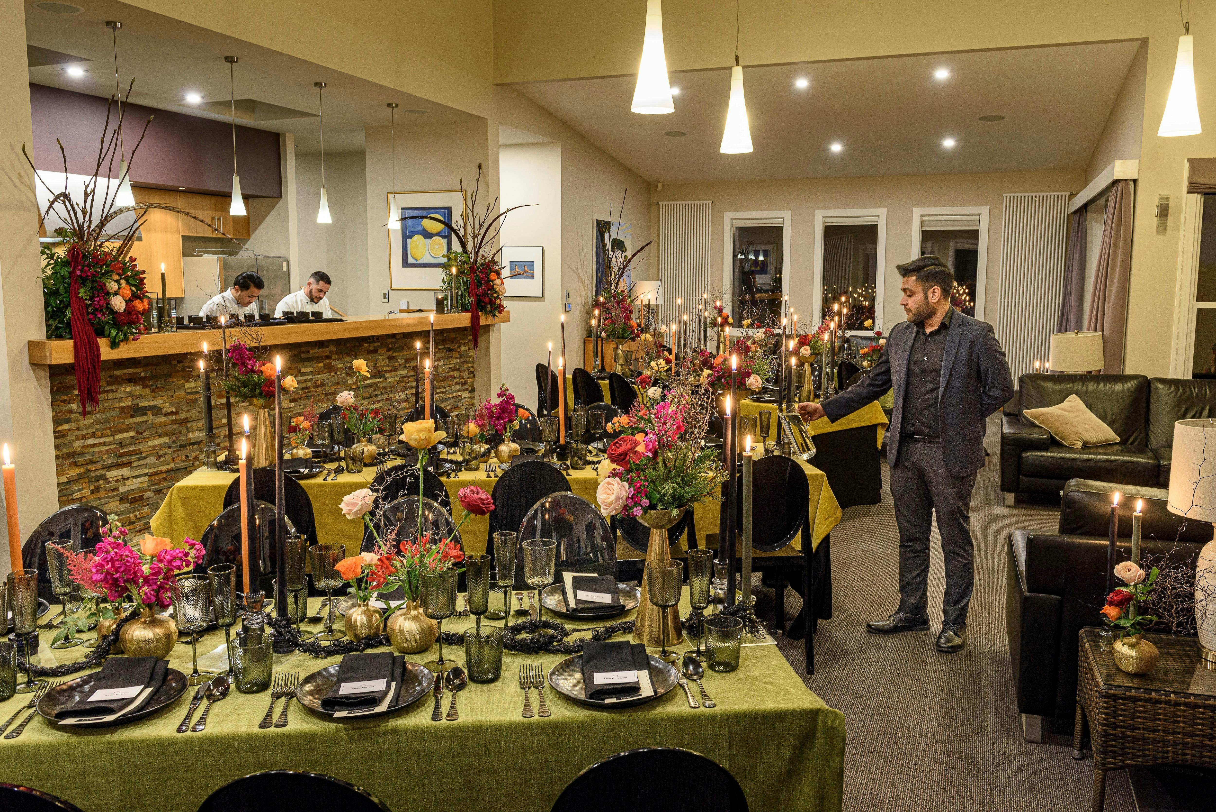 Head waiter lights candles on dinner table
