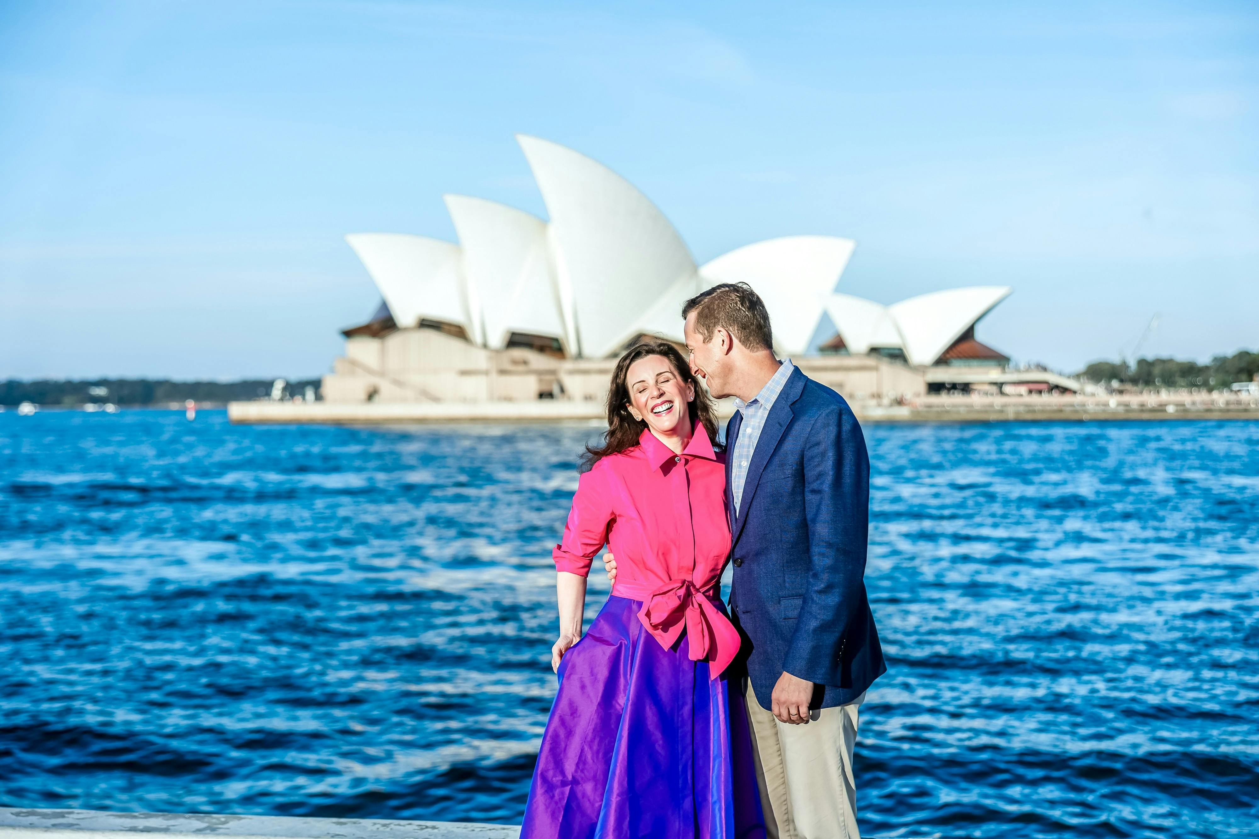 Couple in arms laughing with Opera House in background