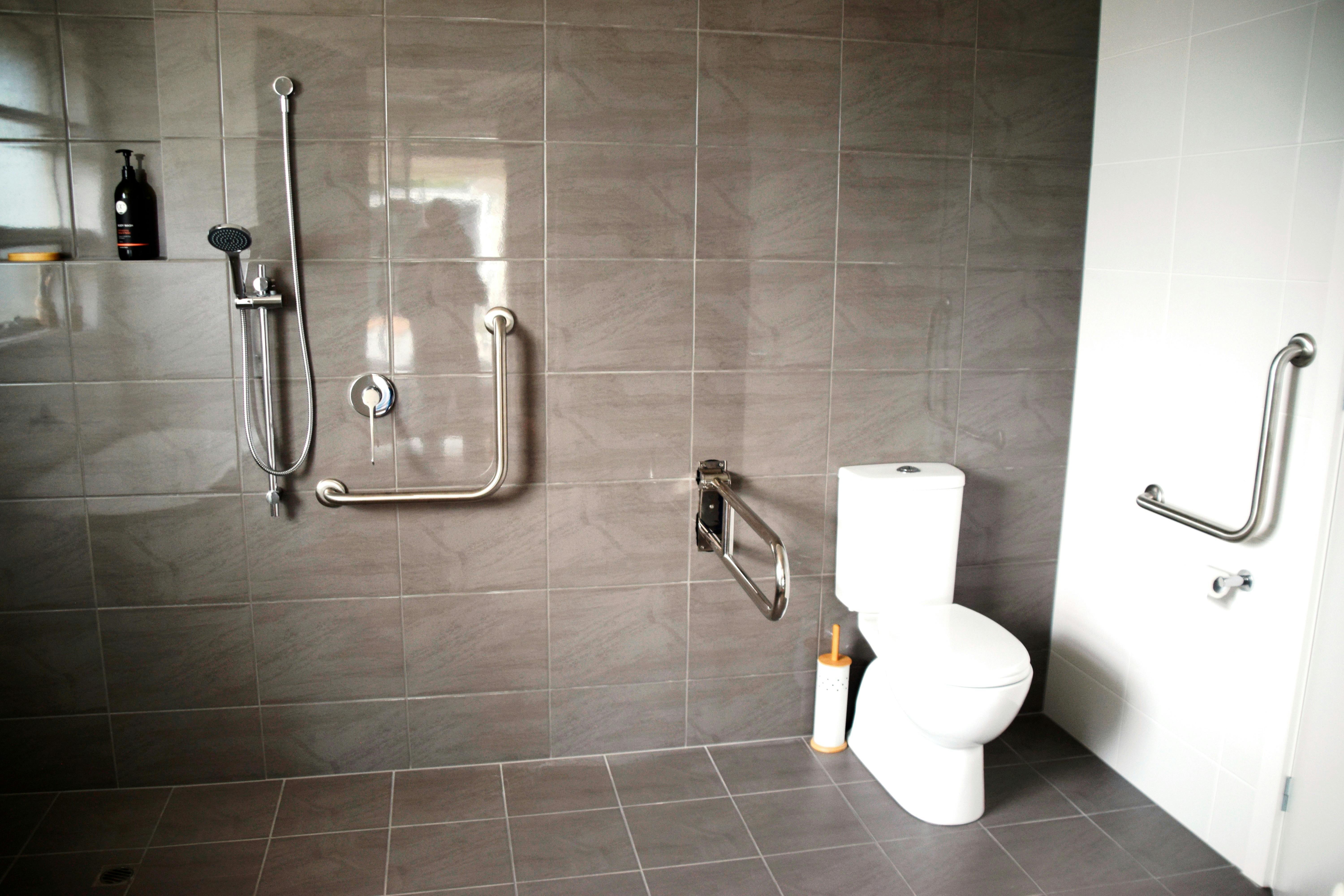 Access Bathroom with rails, left and right, remote raised toilet, lowered hand shower  & no screens.