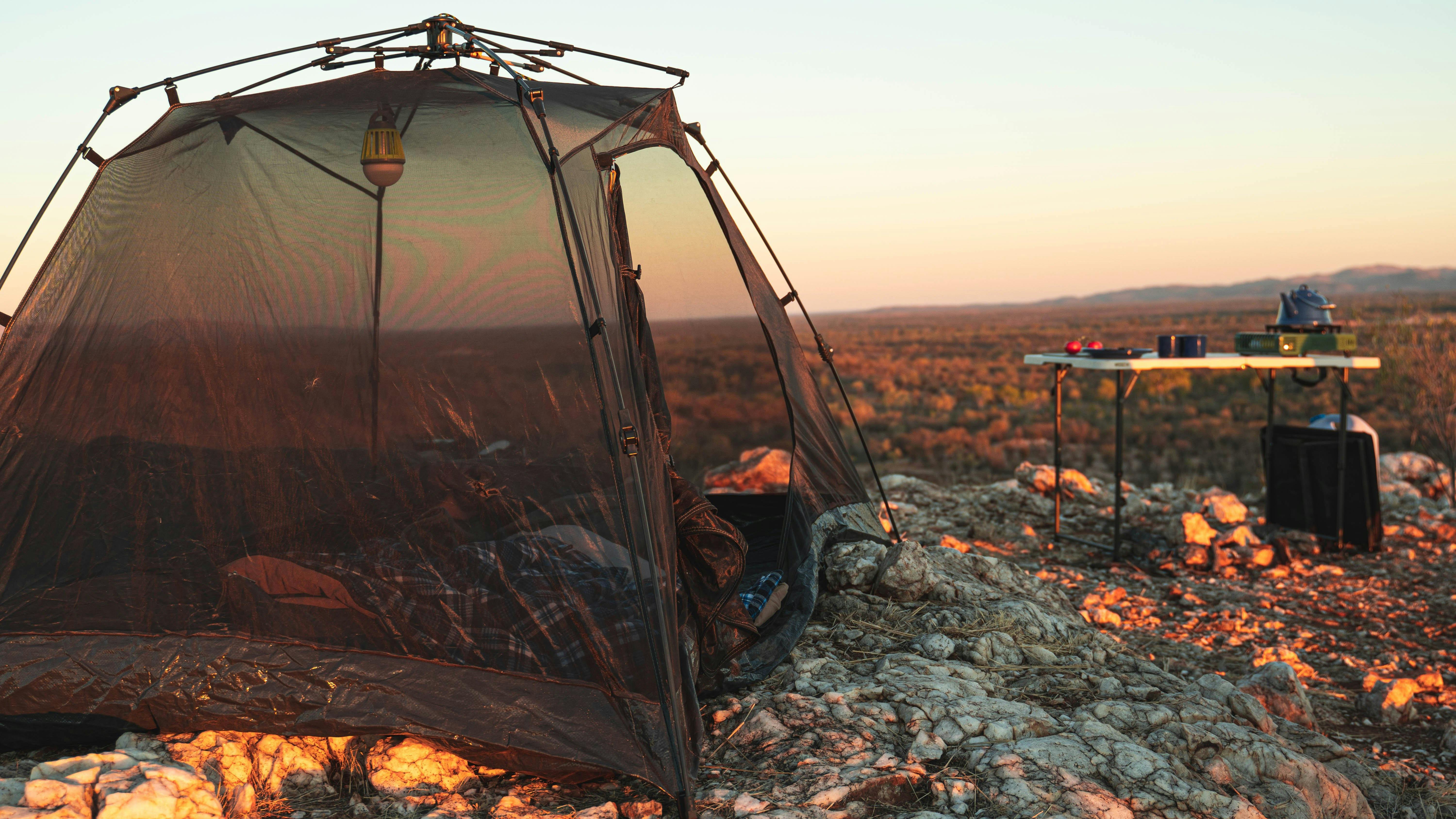 Tent and table on top of a hill at sunset with views over the desert landscape
