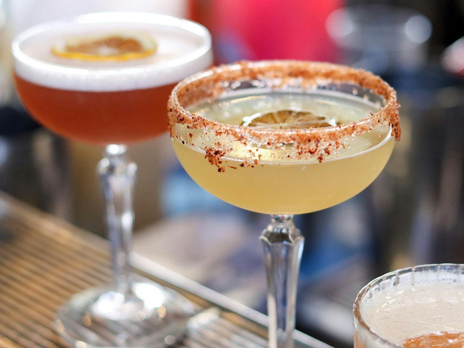 Two cocktails sitting on a bar