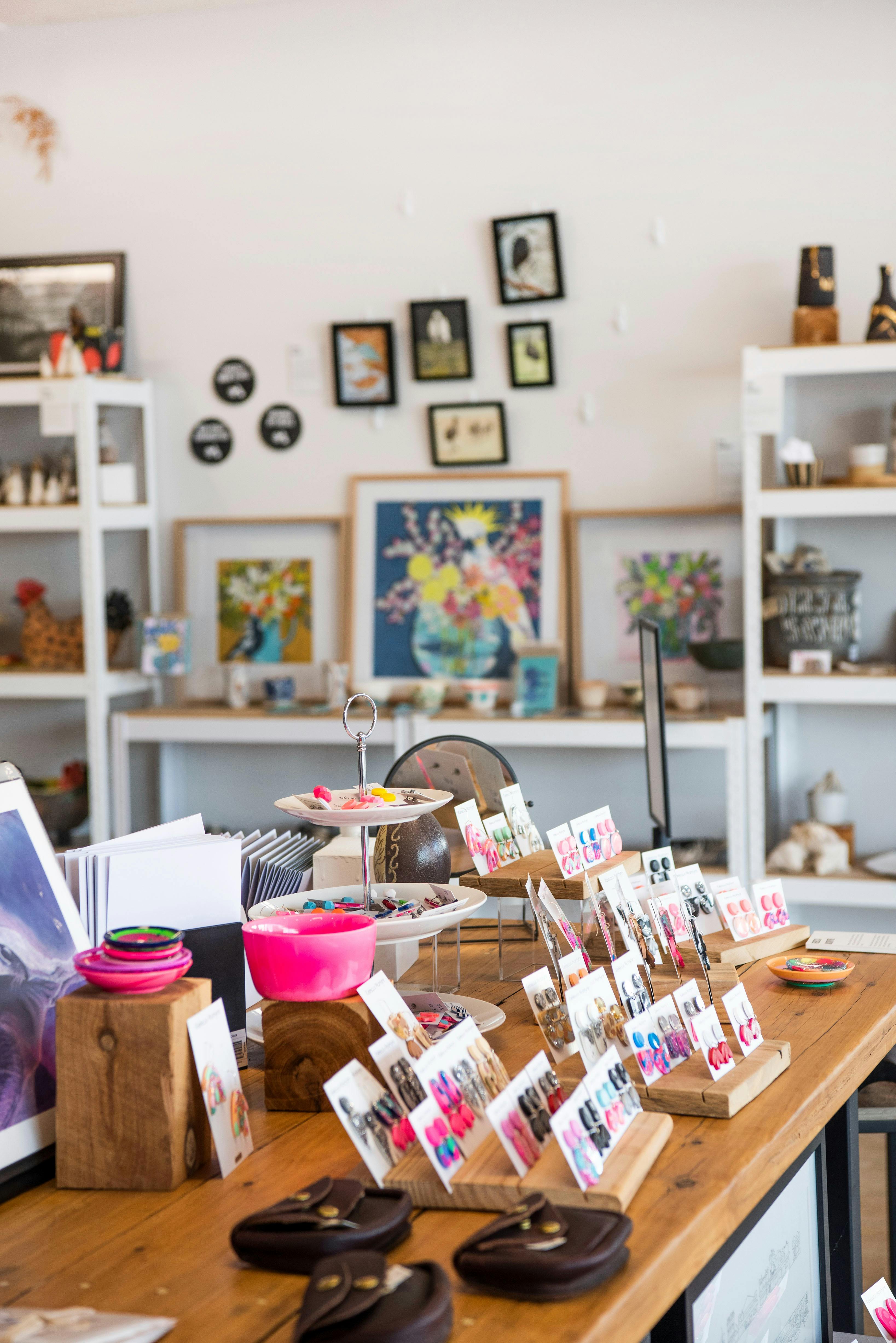 Shop with colorful earrings on display, artwork on walls, and shelves with crafts.