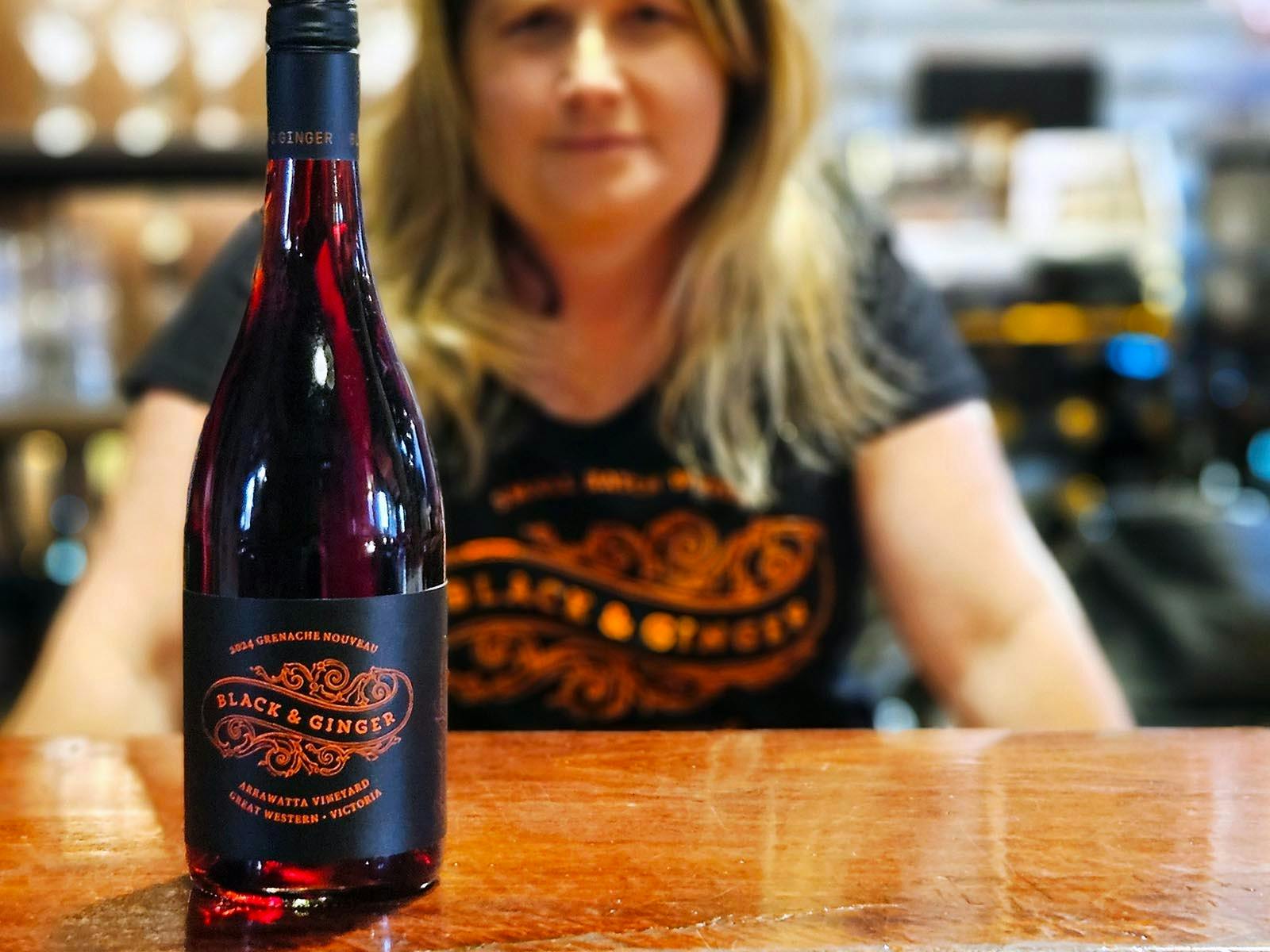A bottle of Grenache Nouveau on the bar at the wine shed, Lucy Black is blurred in the background