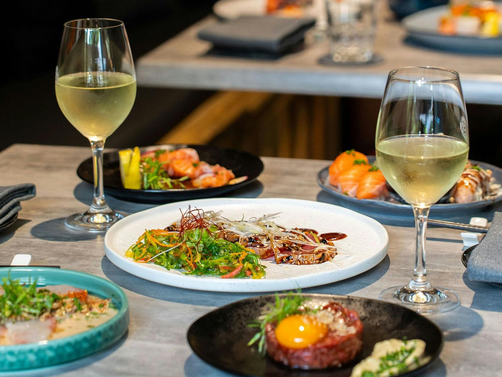 KOI Bar & Restaurant spread of cold bites and two glasses of  white wine.