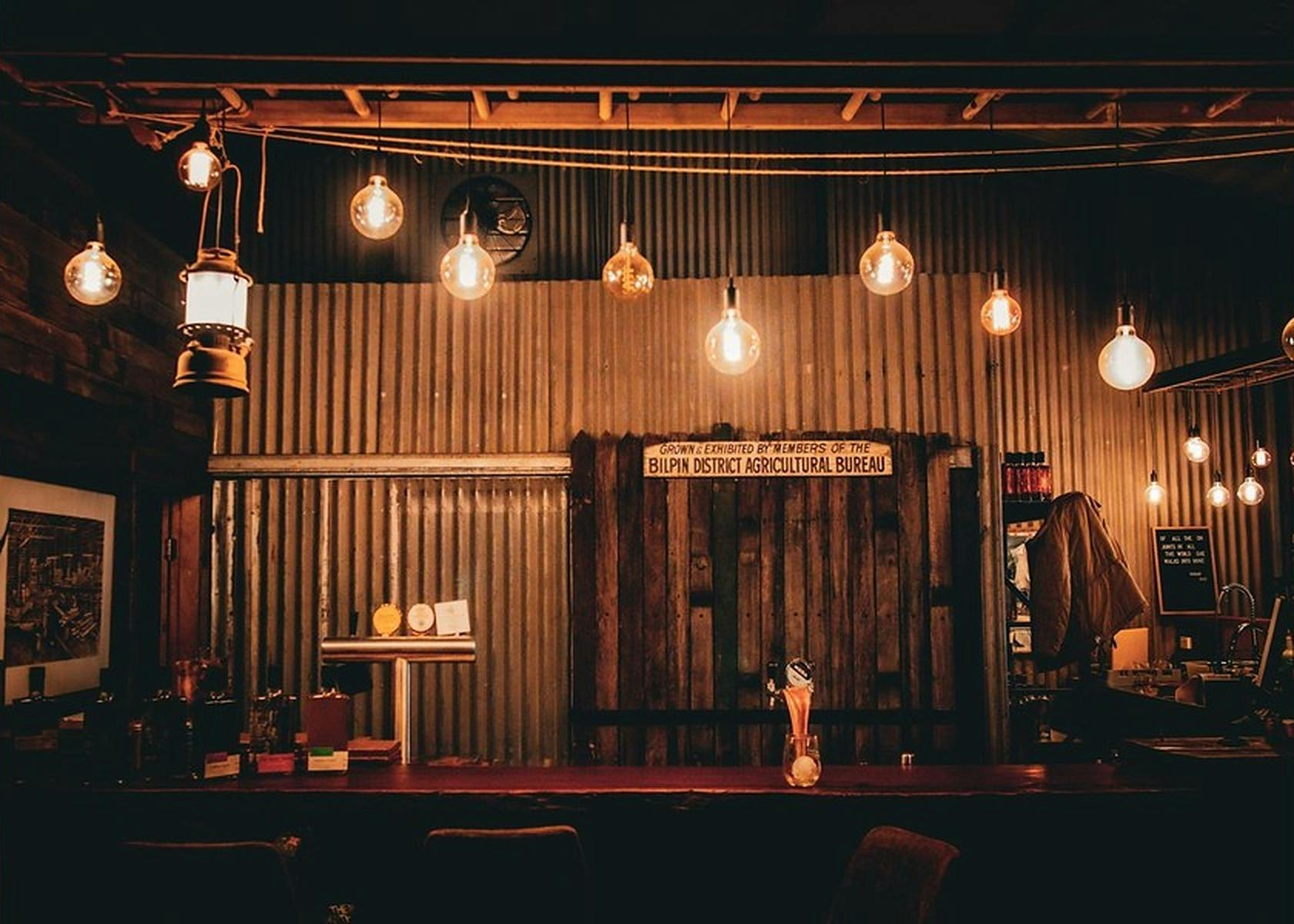 Rustic tin shed tasting bar with hanging Edison lights at Old Shed Distillery
