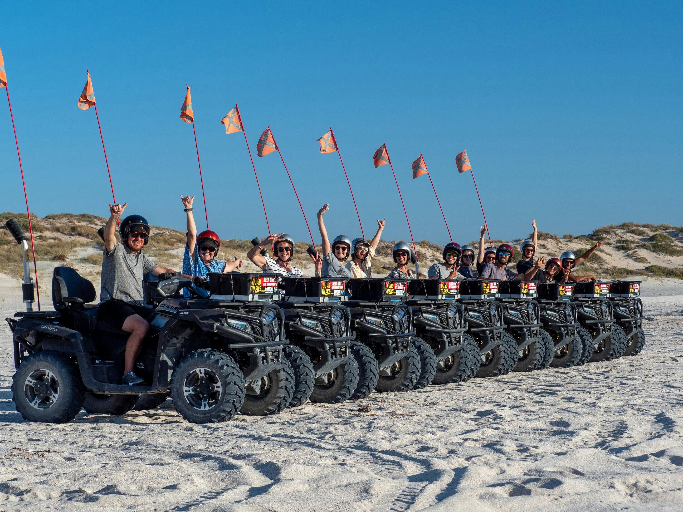 Group of people sitting on quad bikes while parked on the beach