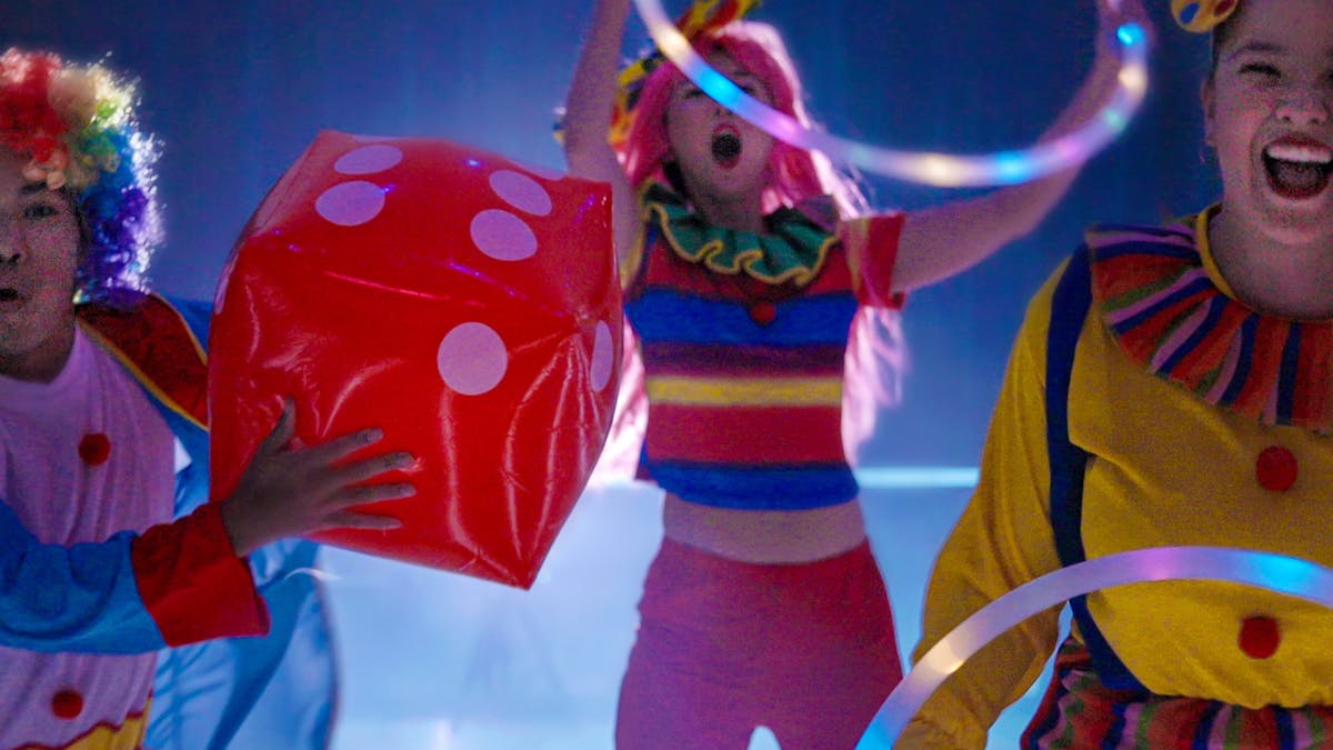 Three colourful clowns on the rink each holding a hula hoop or a red inflatable dice Three colourful clowns on the rink each holding a hula hoop or a red inflatable dice