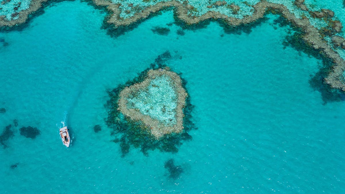 Aerial view showing a boat close to the heart reef and surrounding coral in sea