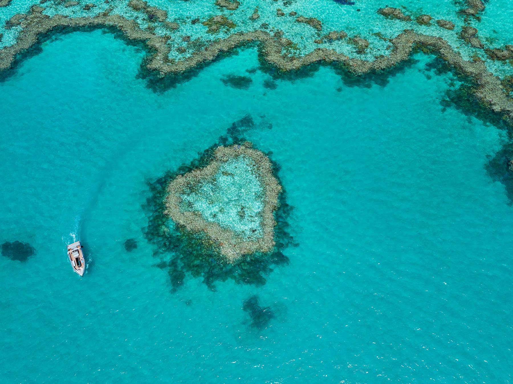 Aerial view showing a boat close to the heart reef and surrounding coral in sea