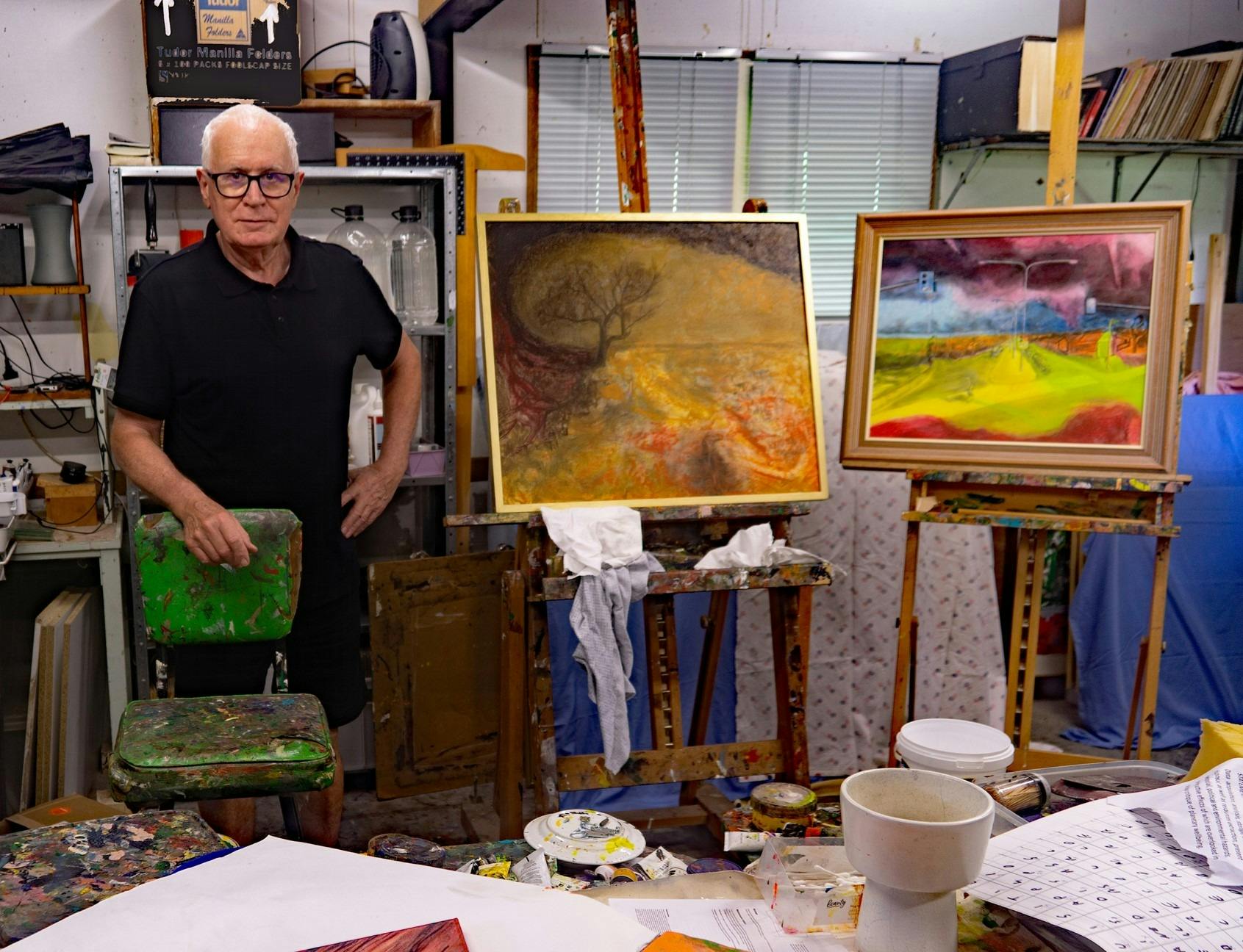 Artist in his studio with some of his paintings