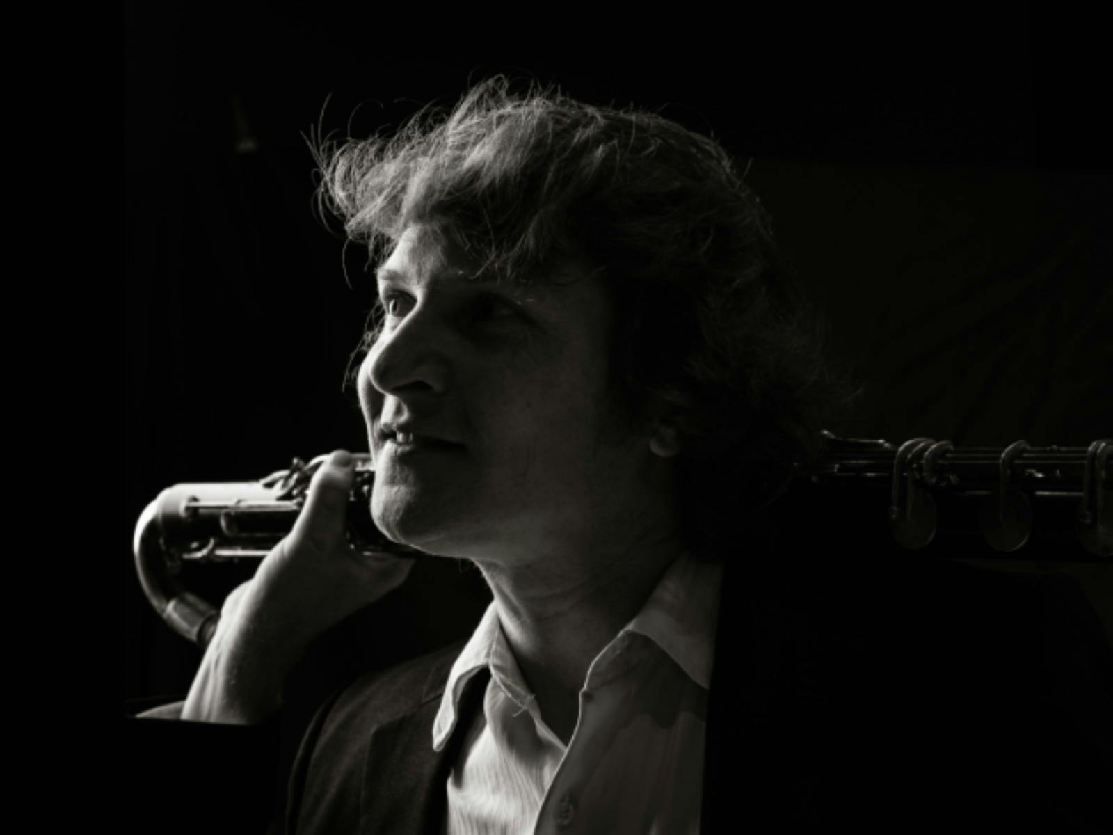 Black-and-white portrait of a bass clarinet player in profile, looking toward the light