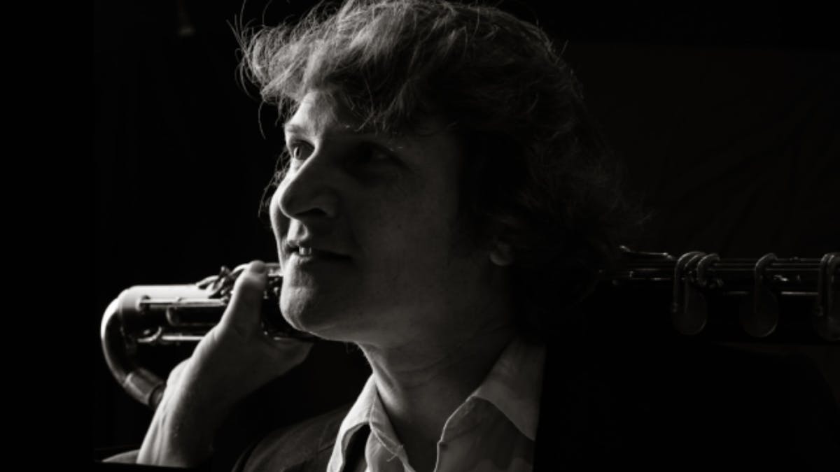 Black-and-white portrait of a bass clarinet player in profile, looking toward the light