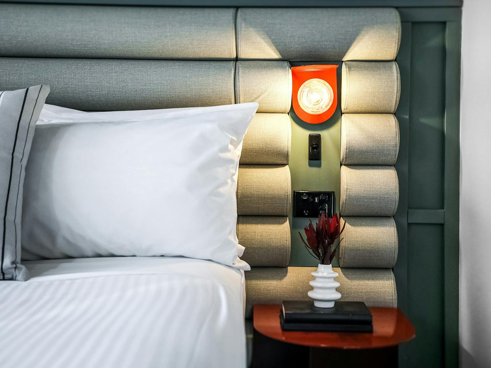 깨끗한 흰색 시트와 침대 머리판 침대 옆 탁자가 놓인 호텔 침대의 클로즈업