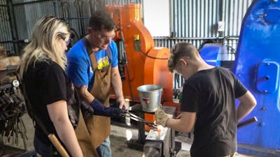 Man and children blacksmithing on an anvil