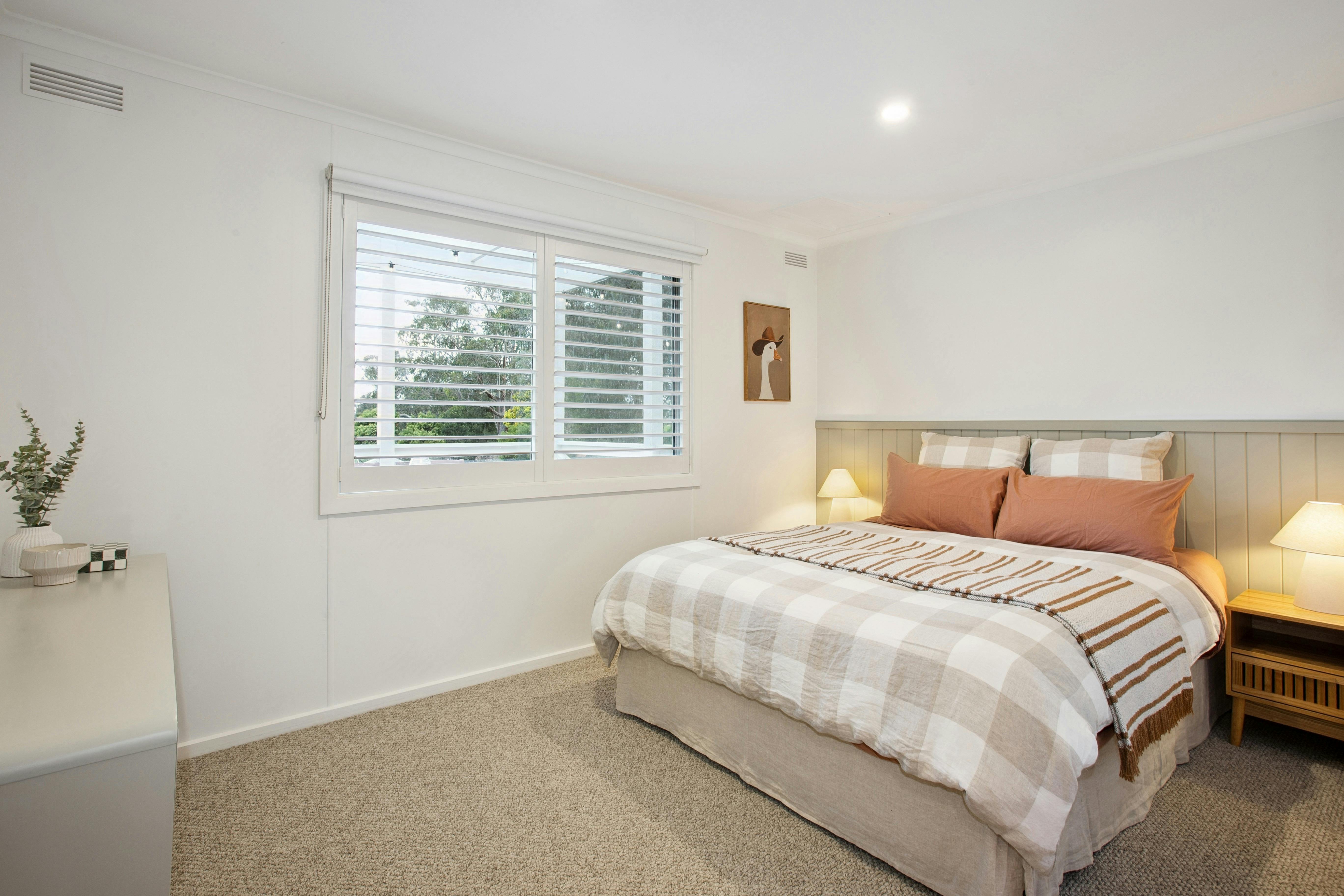 Main Bedroom with earthy linen bedding, bedside lamp and quirky artwork goose in a cowboy hat.
