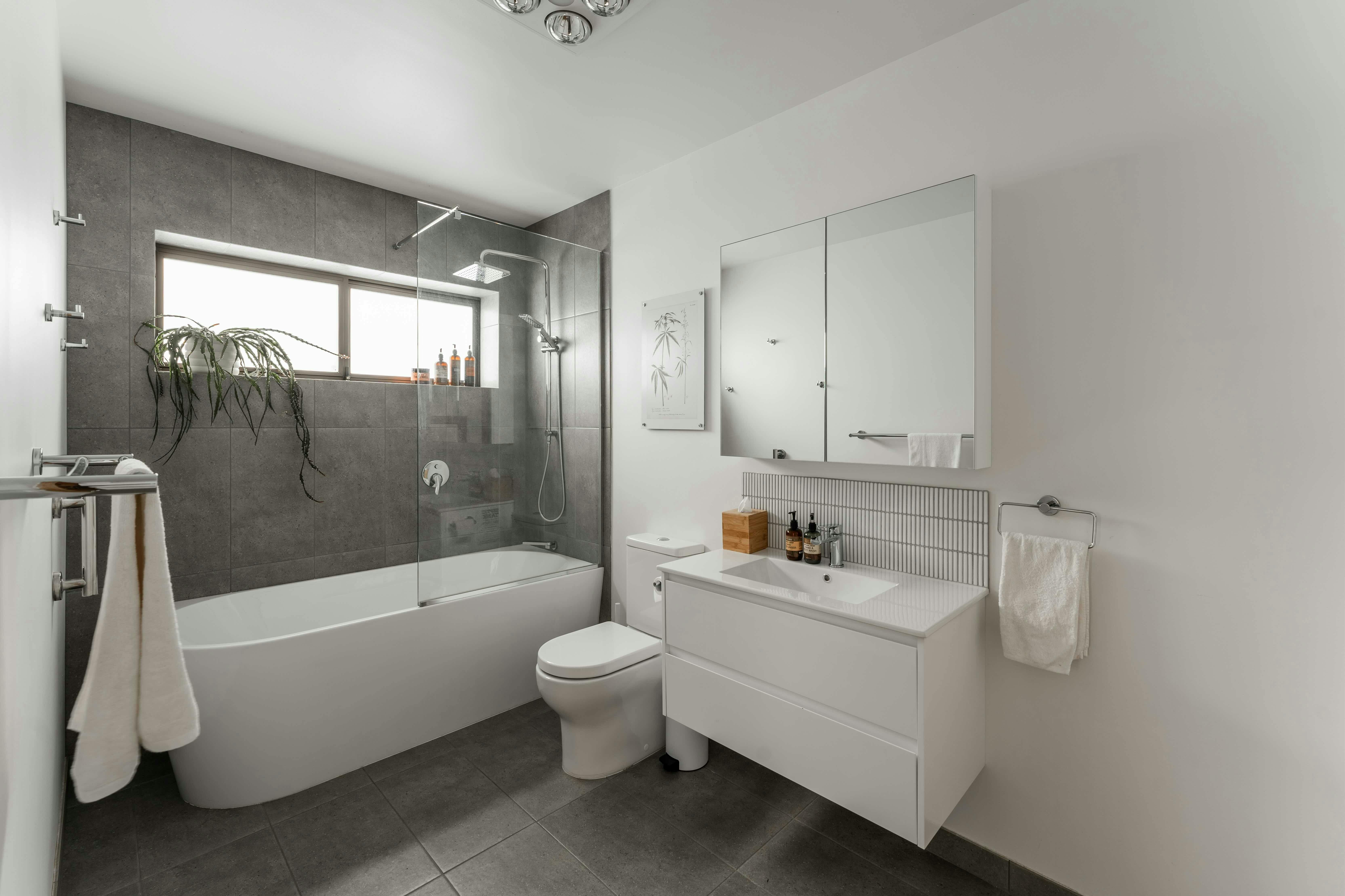 A modern bathroom with a deep tub and shower, vanity unit and toilet.