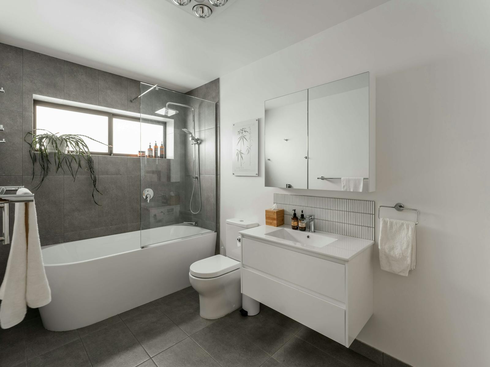 A modern bathroom with a deep tub and shower, vanity unit and toilet.