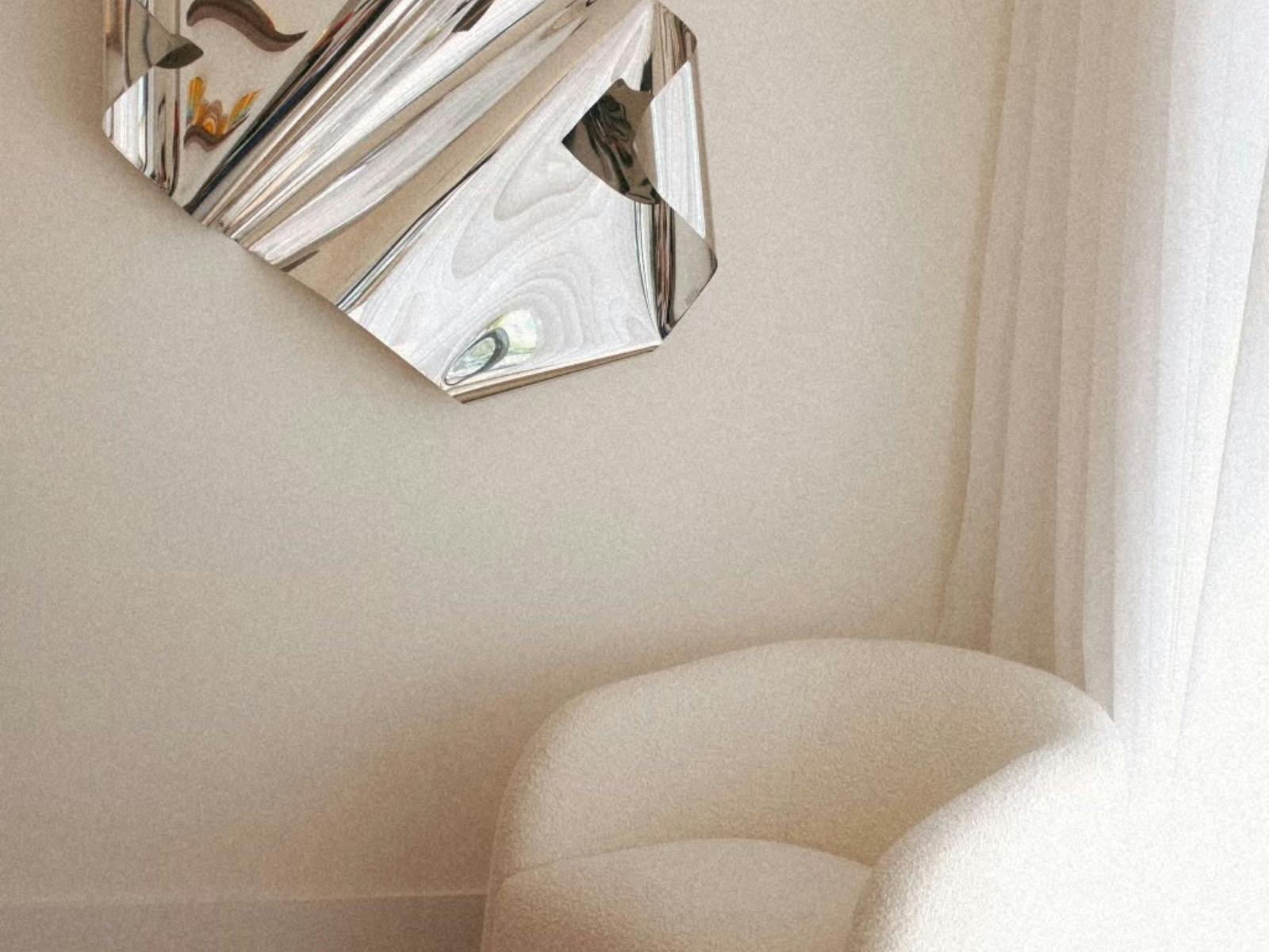 Picture of white armchair with silver sculpture on the wall