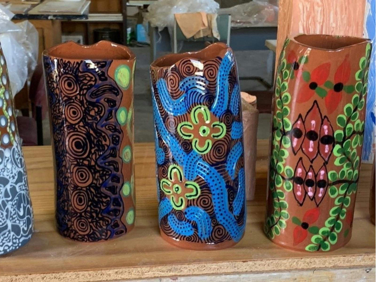 Hand-painted pottery with vibrant Indigenous designs in earthy and colorful patterns on display.