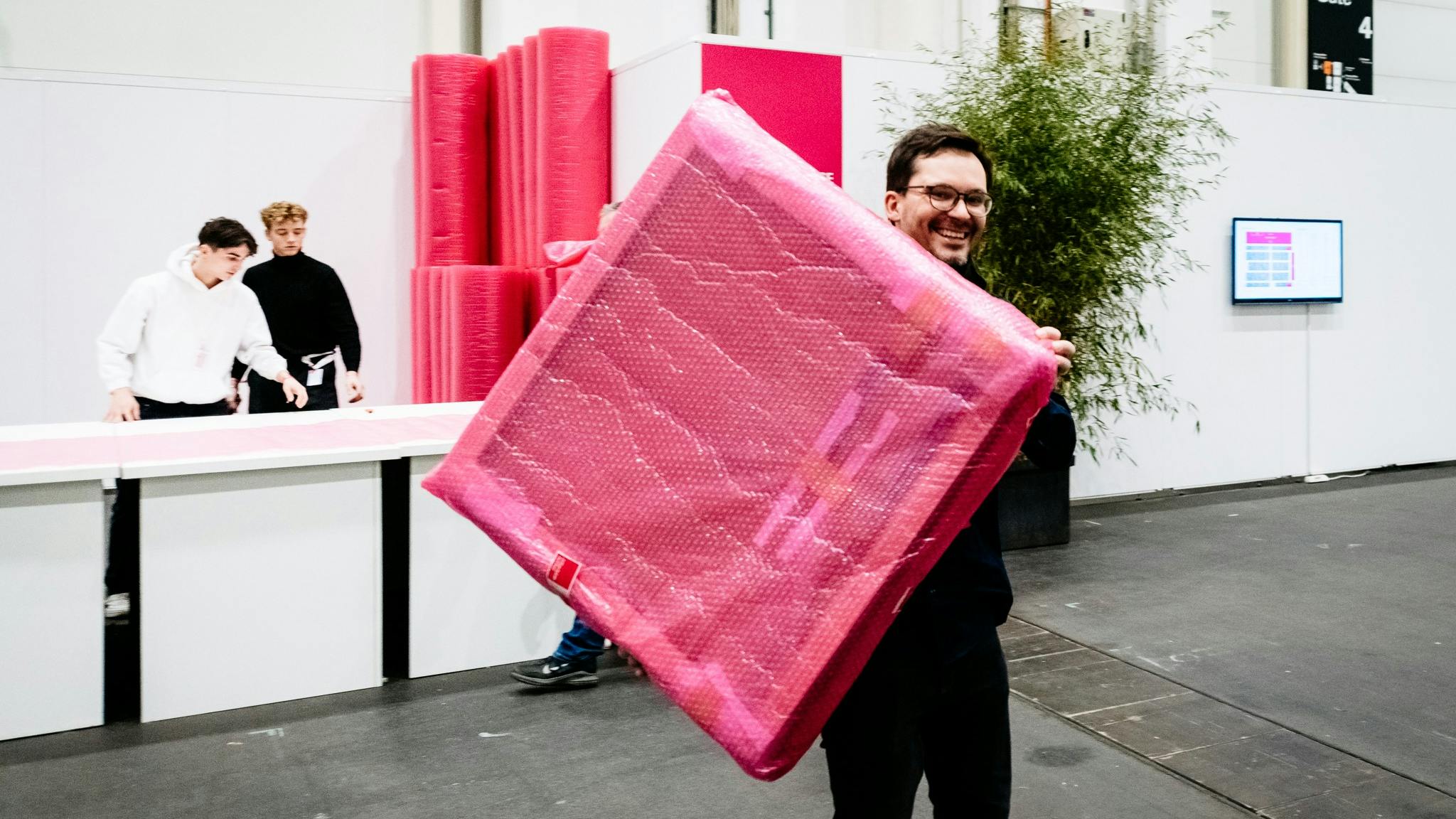 Visitor at an Affordable Art Fair holding a painting wrapped in hot pink bubble wrap after purchase