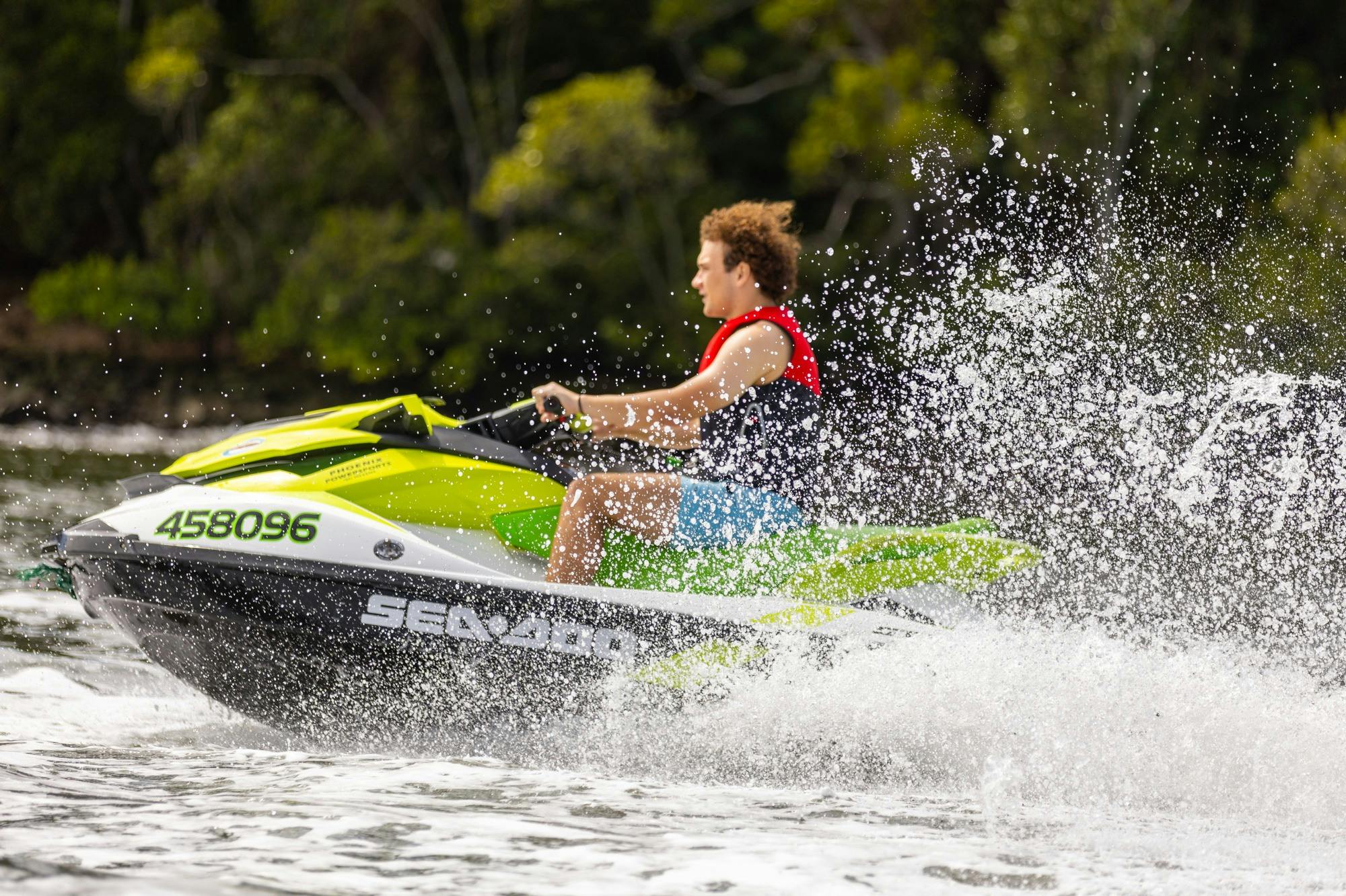 Male cruising through the Brisbane River on a jet ski smiling and having fun