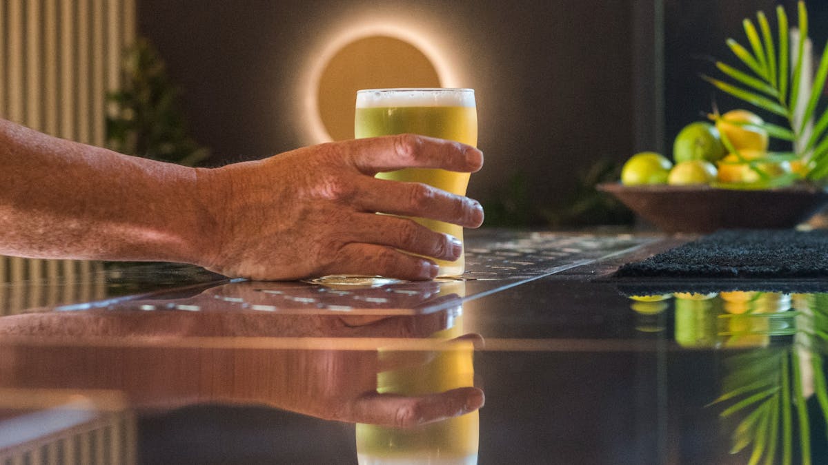 Hand reaching for a beer at the bar counter