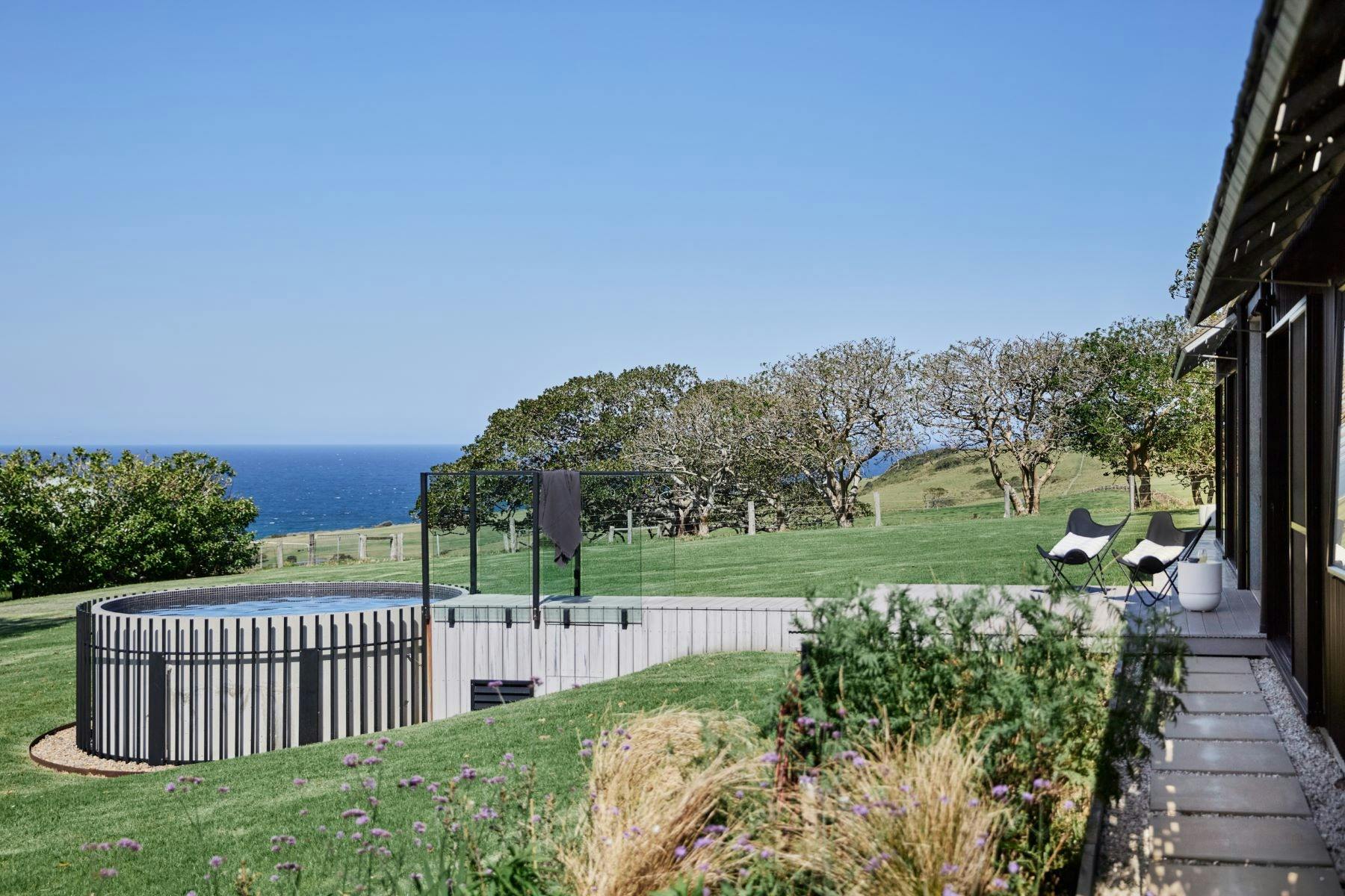 Image of pool during the day. It is sunny . The pool is to the left and deck leading towards house.