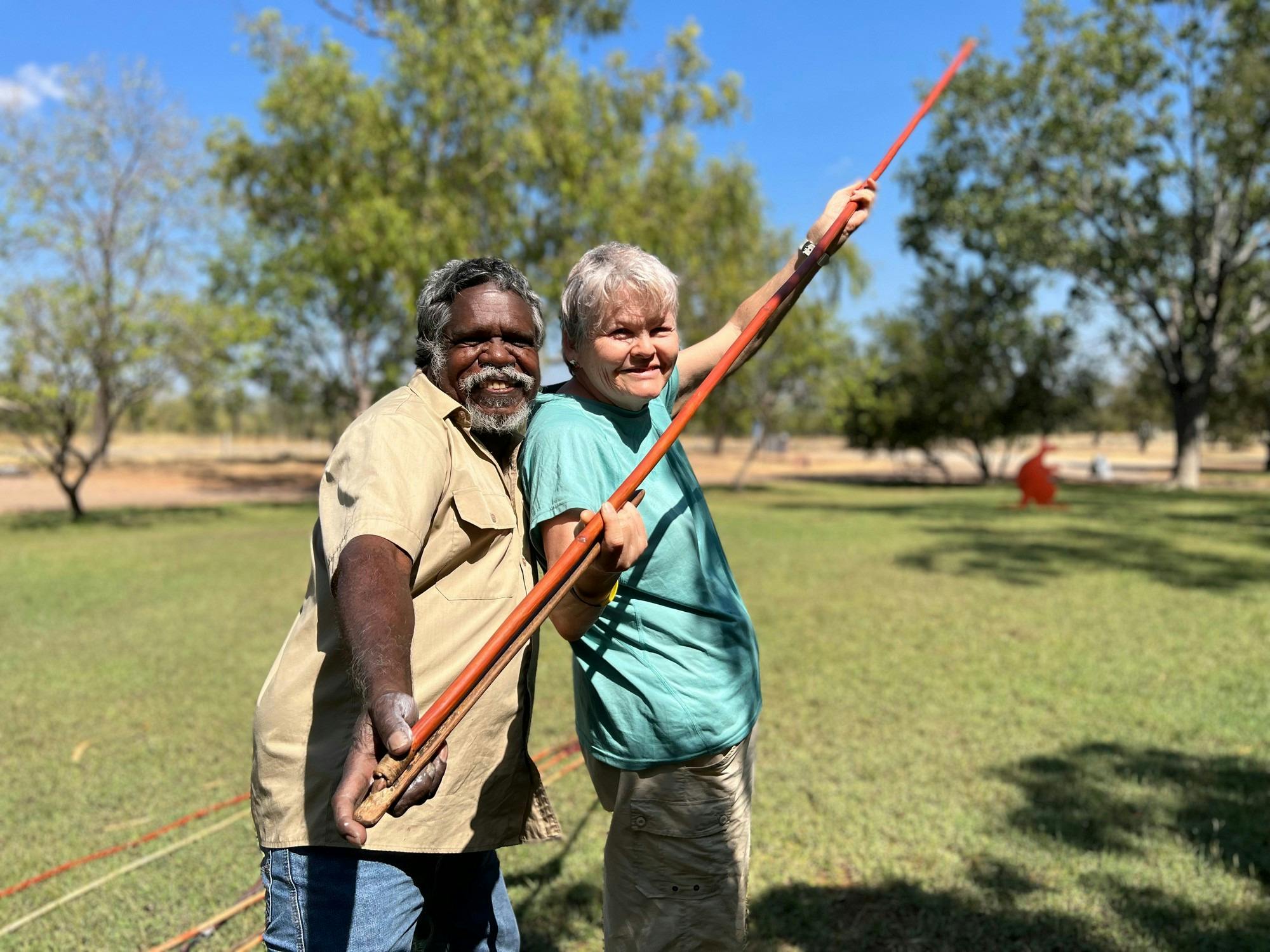 lady being tought to throw spear by aboriginal man