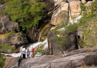 Three people standing at granite rock lookout watching a waterfall.