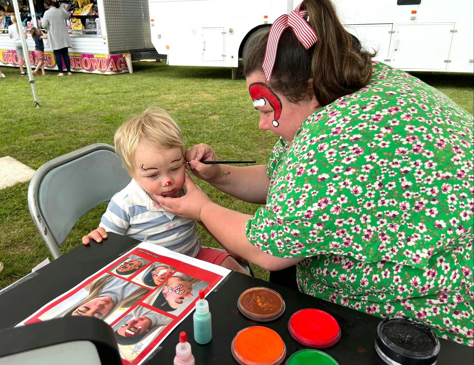 A boy getting a Christmas theme painted on his face.
