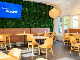 Indoor dining area known as The Deck with booths, timber tables and green feature wall