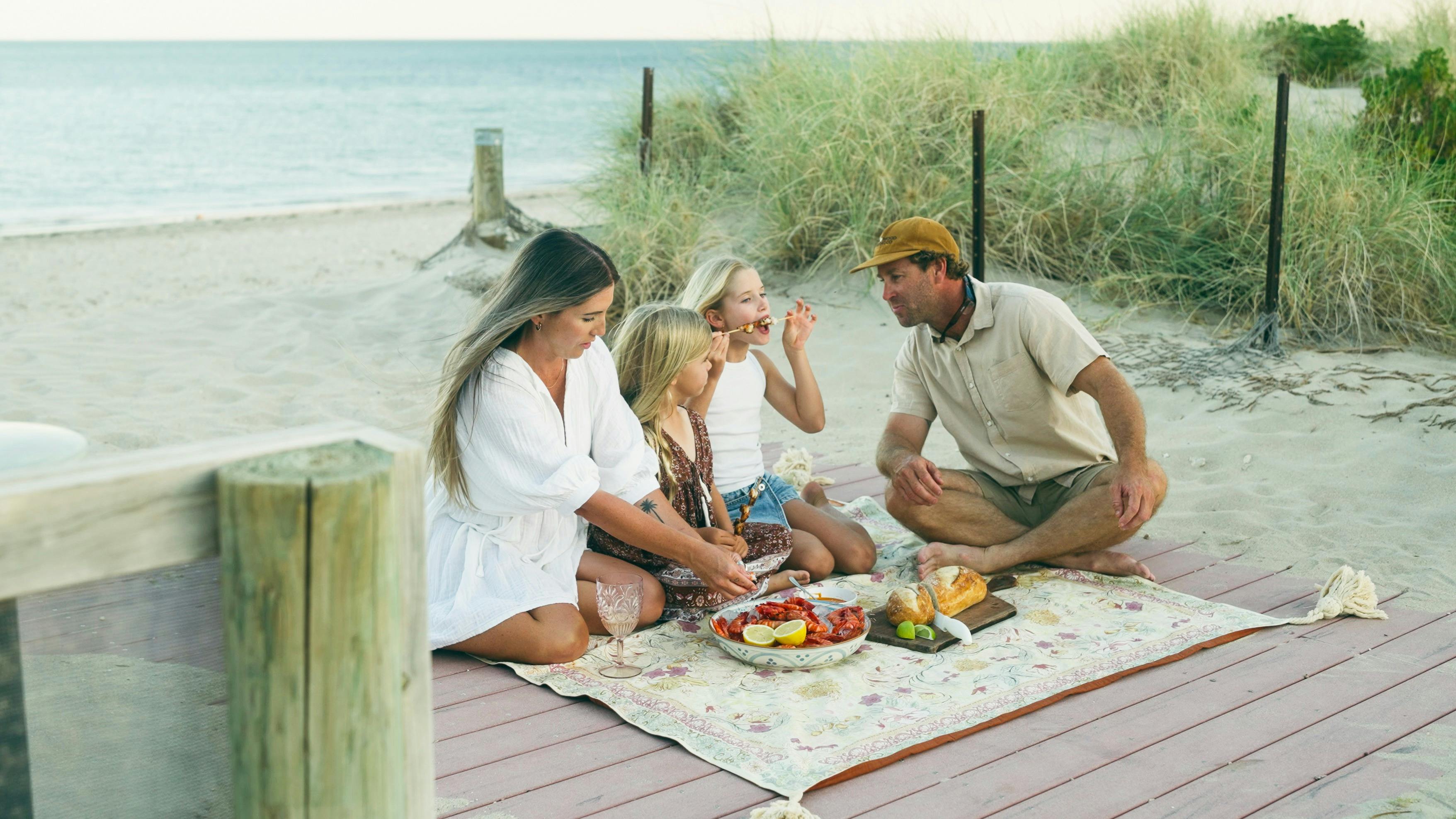Family enjoying a picnic on the beach enjoying prawns