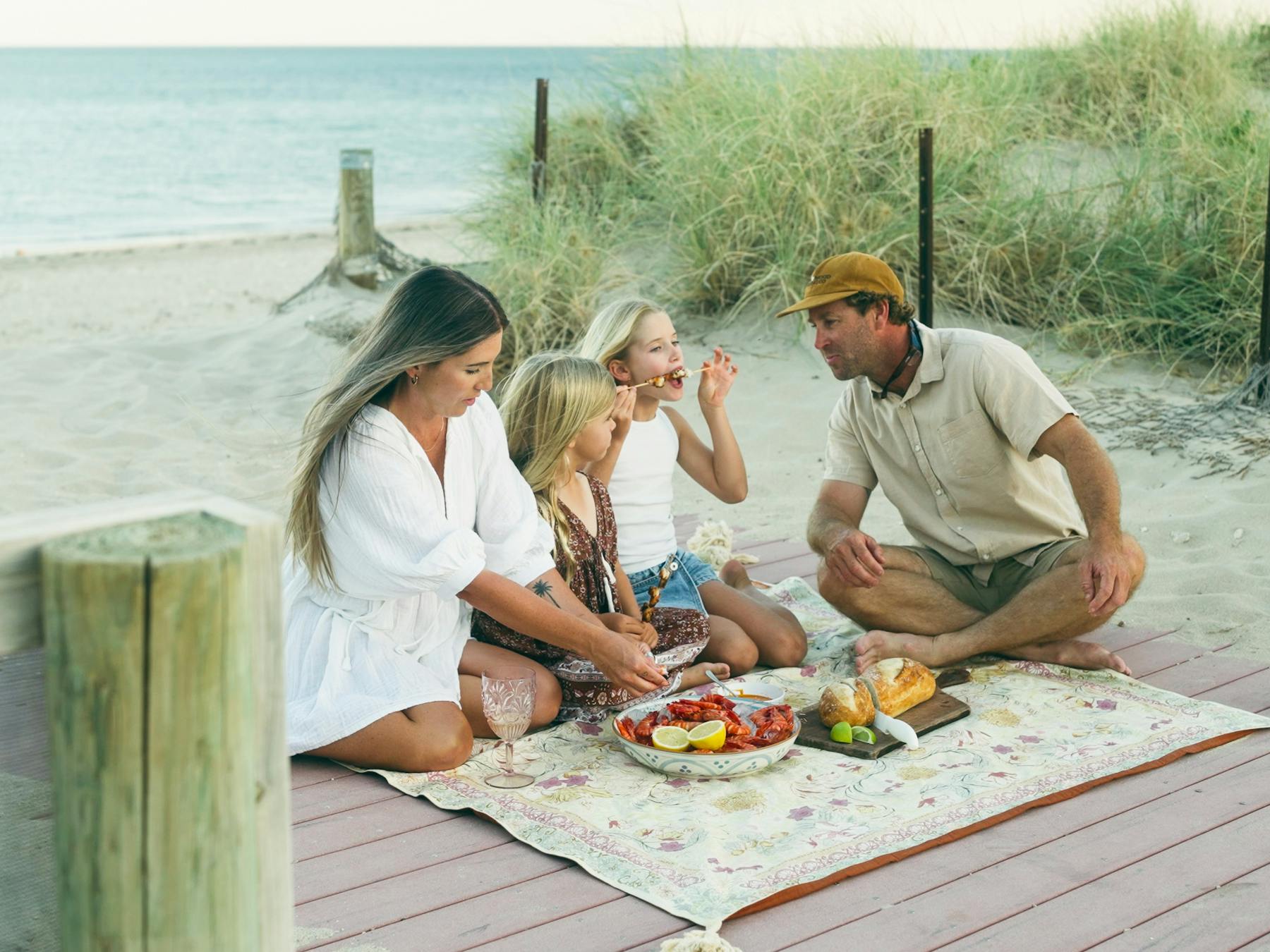 Family enjoying a picnic on the beach enjoying prawns