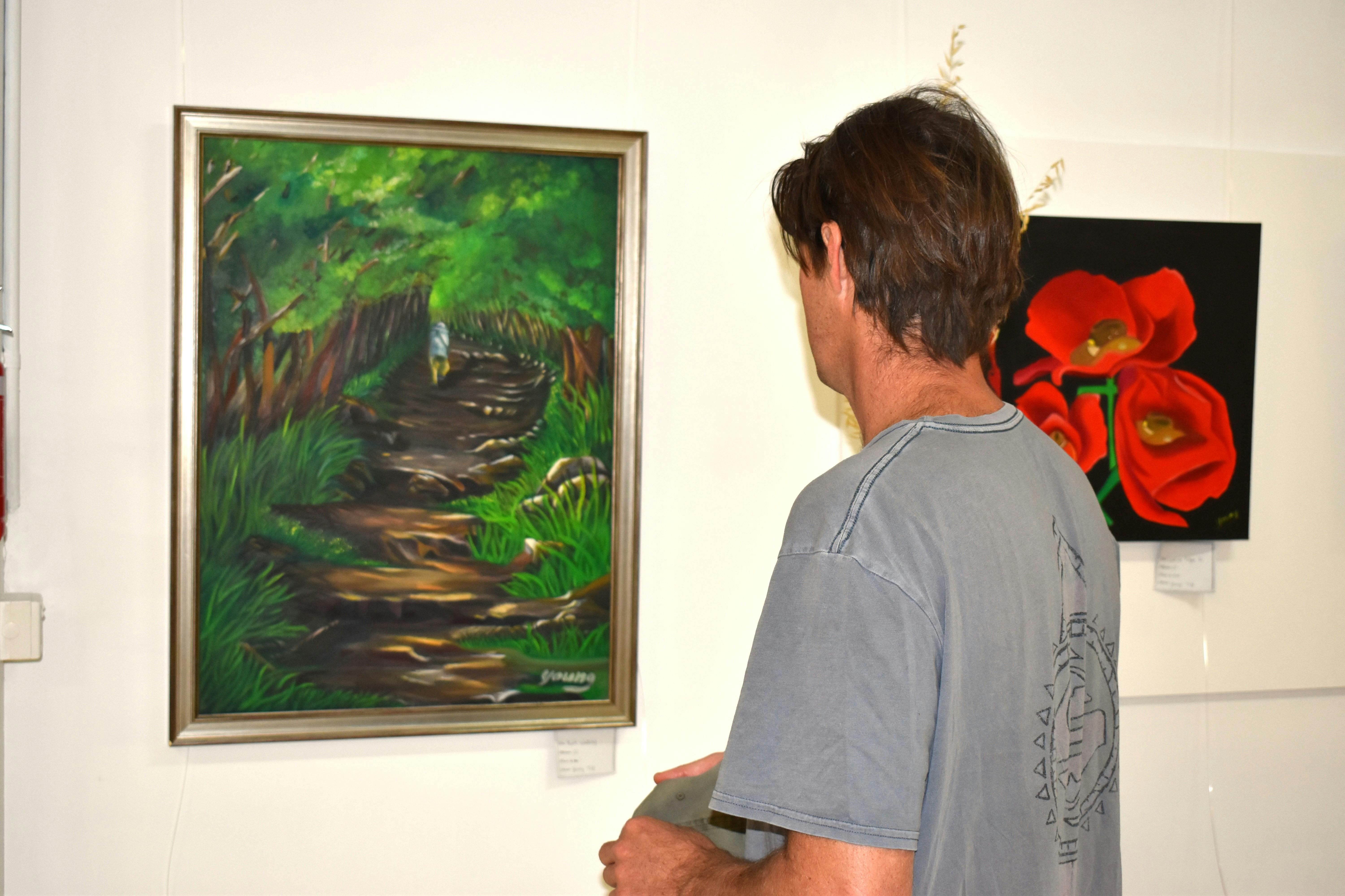 숲 속의 길을 묘사한 예술 작품을 보고 있는 방문객.