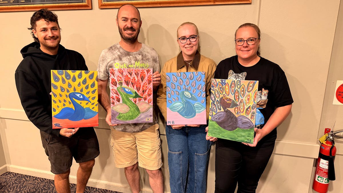 Group of Paint Juicy guests holding their finished peacock paintings at a mobile paint and sip event
