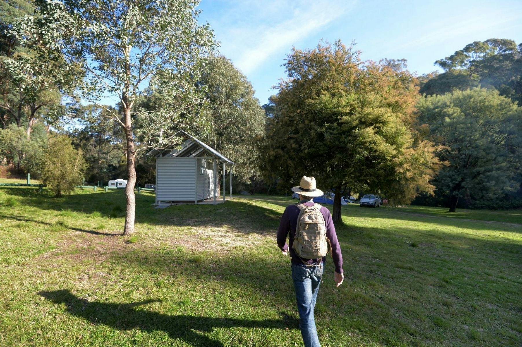 A person walking towards an amenity block at a forest campsite