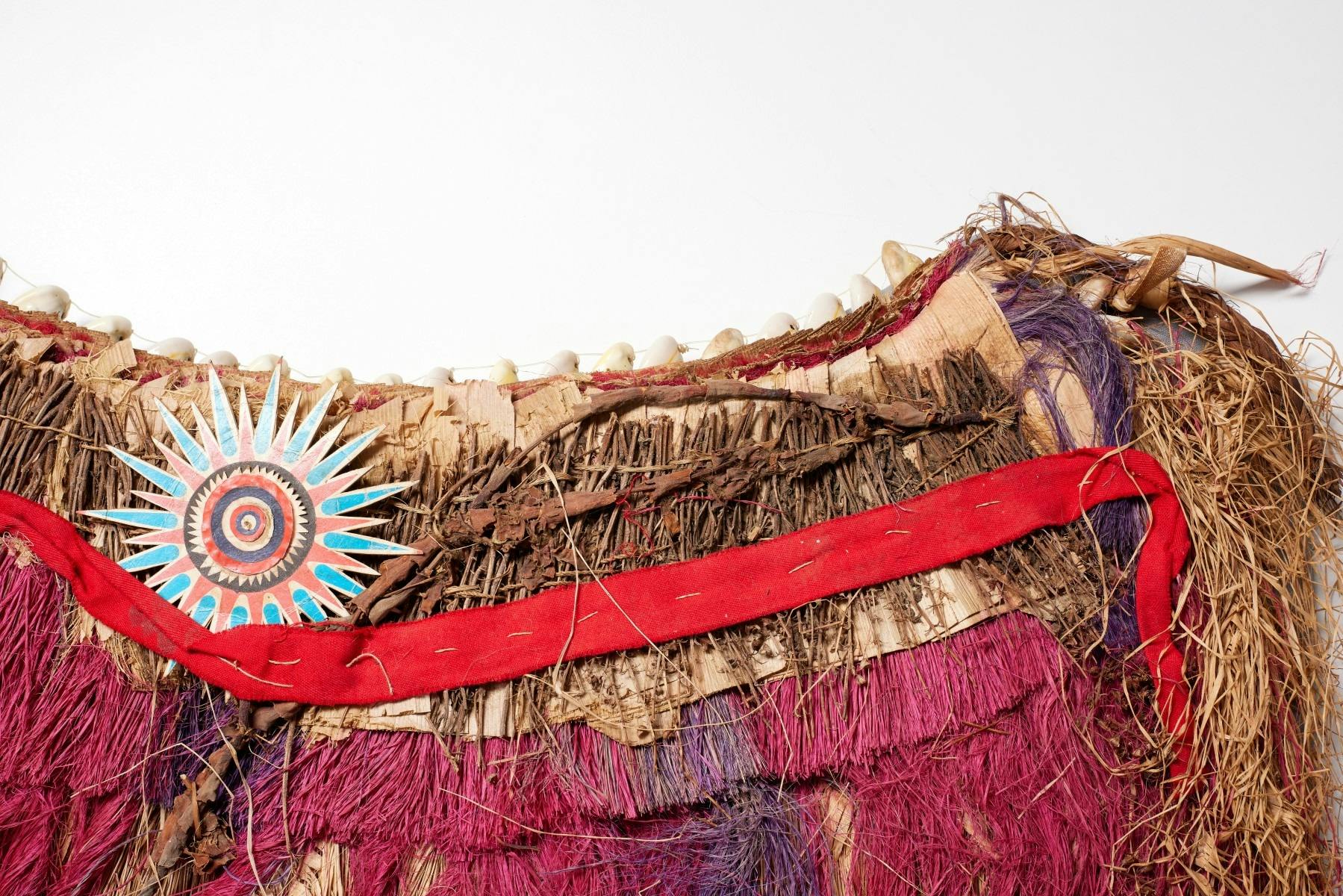 Skirt made of pink, purple and natural banana leaf fibre with twigs and cowrie shells.